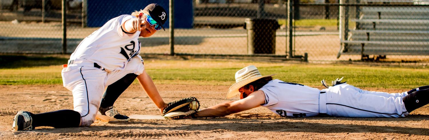 Baseball players diving and reaching for a base during a competitive play.