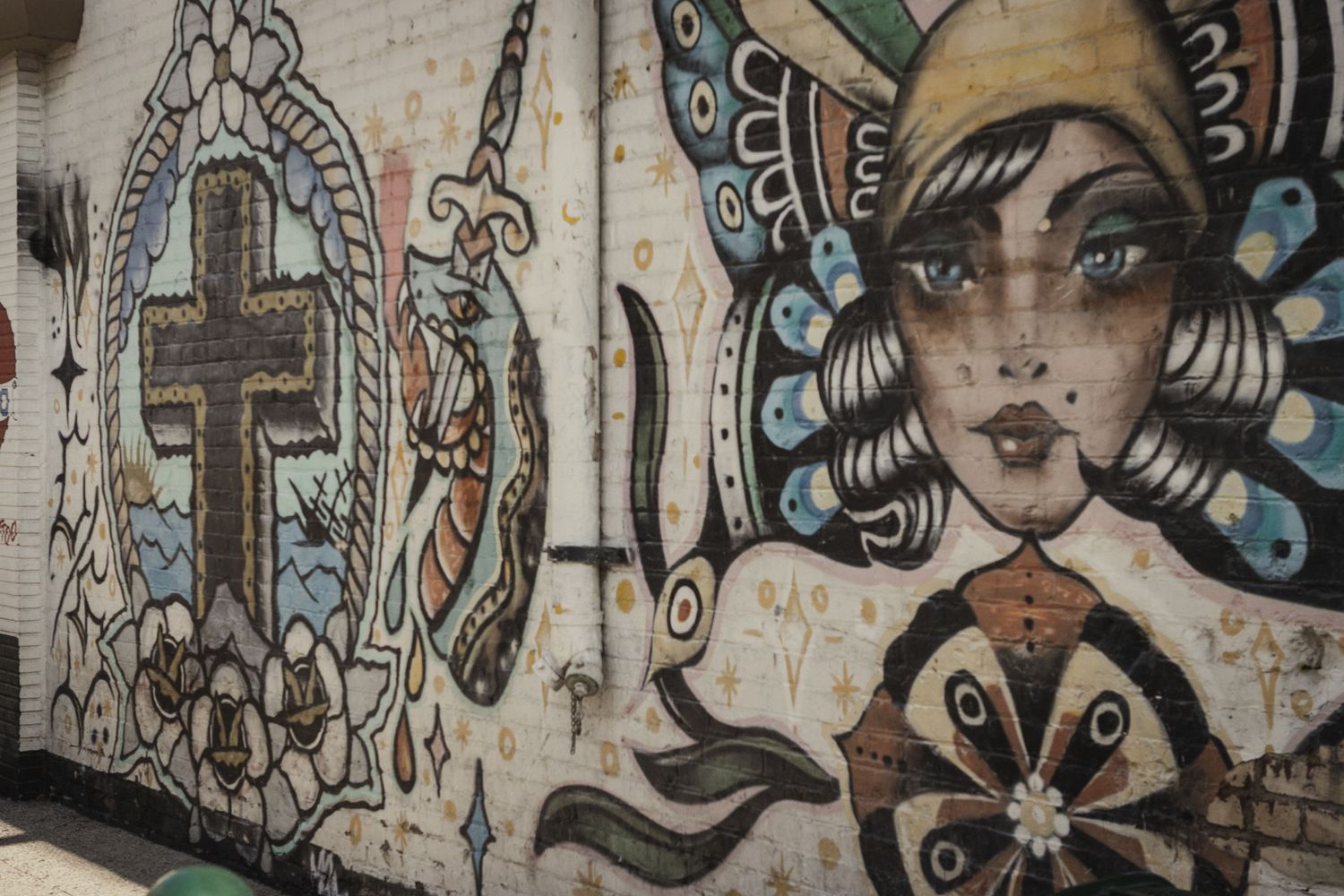 Urban street art mural featuring abstract symbols and butterfly motifs painted on a textured wall.