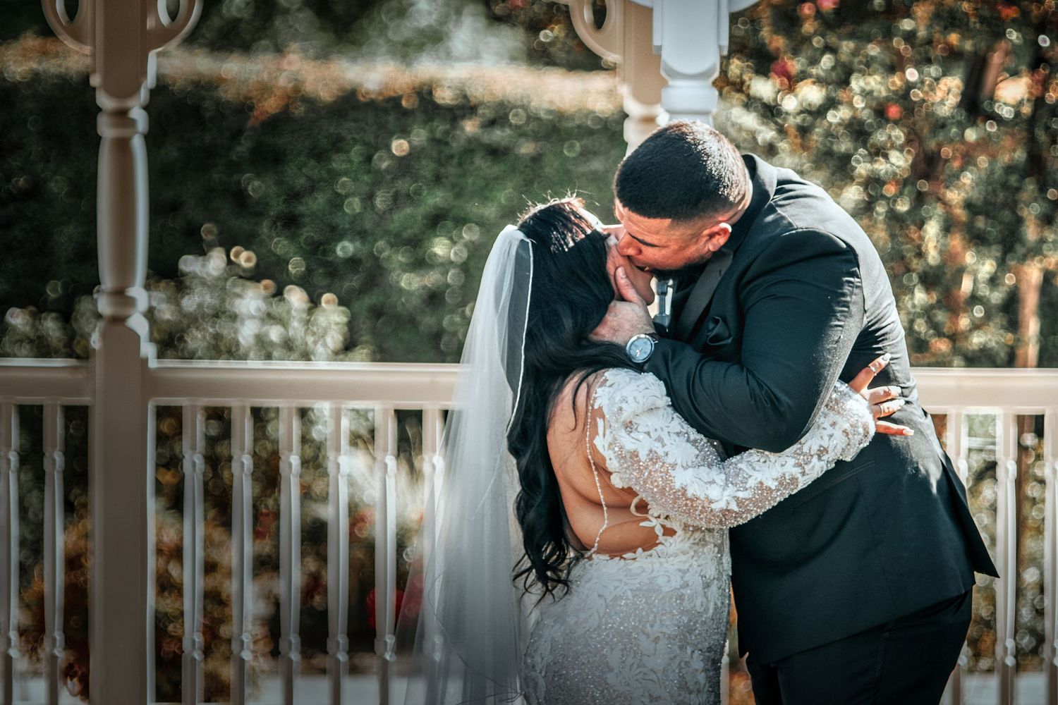 A romantic moment shared between a couple on a white porch during their wedding day.