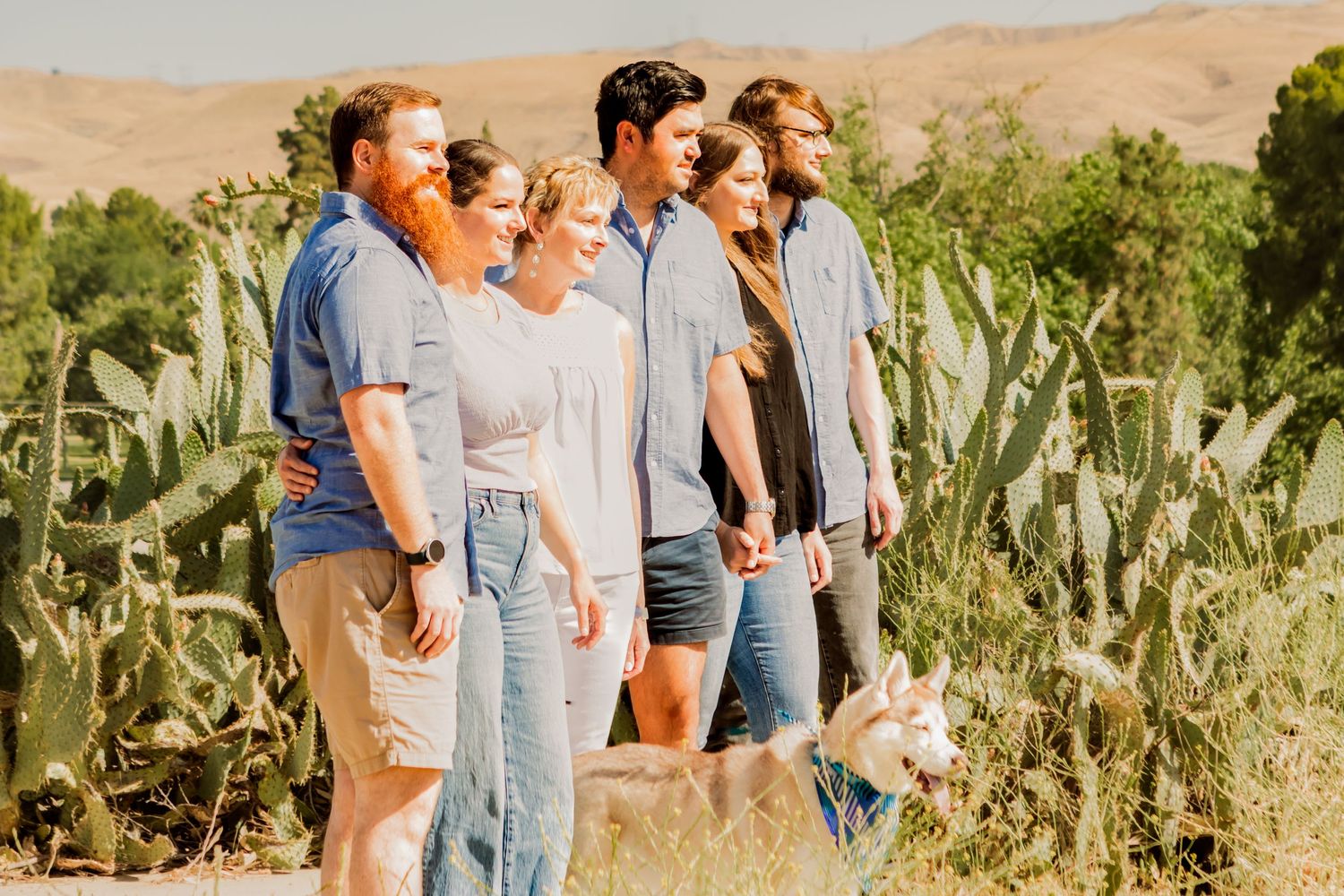 Group standing together at sunset with desert mountains and cacti in background.