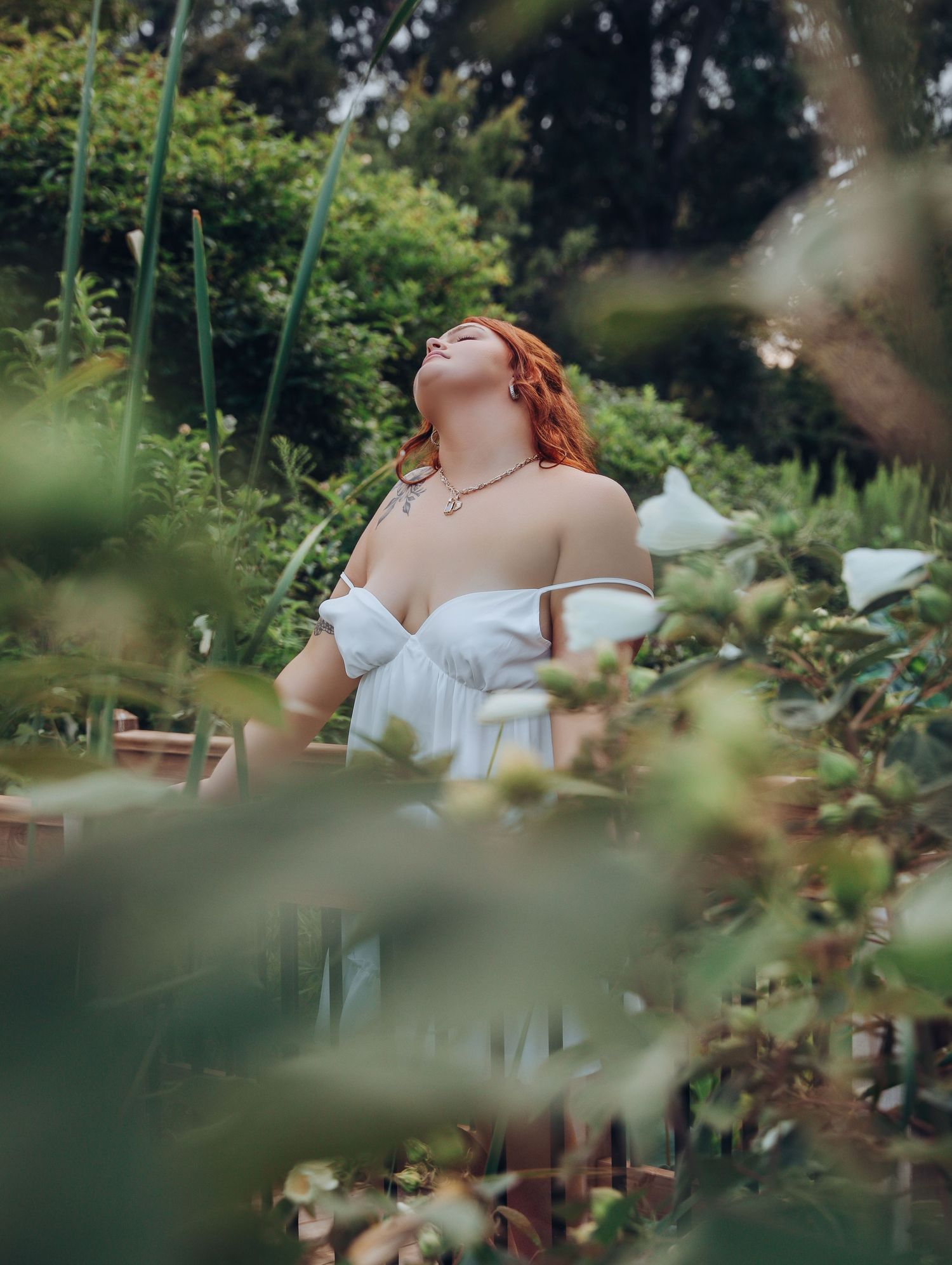 Beautiful young woman with red hair bridal session outdoor boudoir posing with white gown slipping off shoulders at park Boudoir by Bri STL