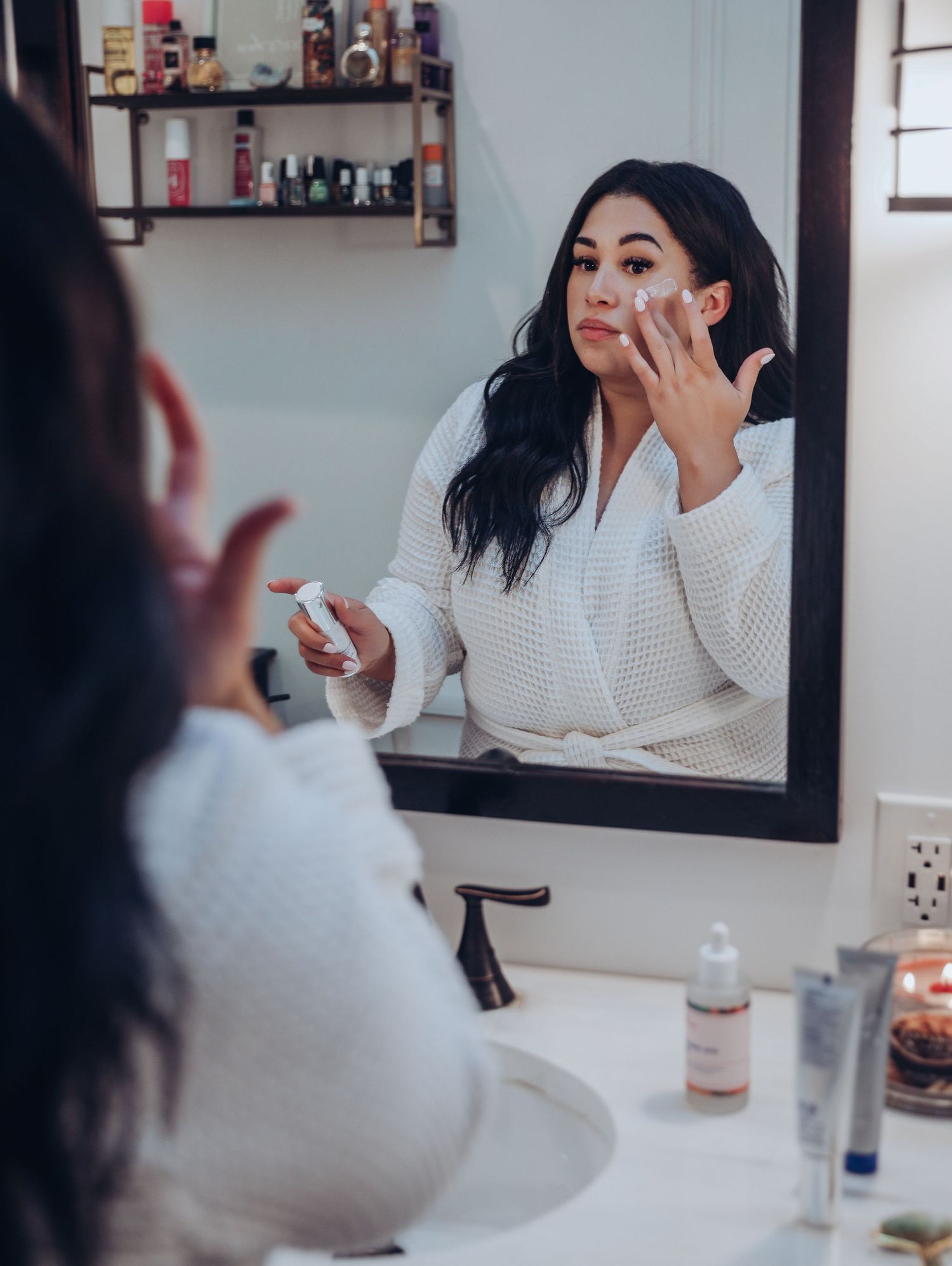 Boudoir by Bri photoshoot of small business branding and headshots of local esthetician doing skincare in mirror wearing robe in St. Louis