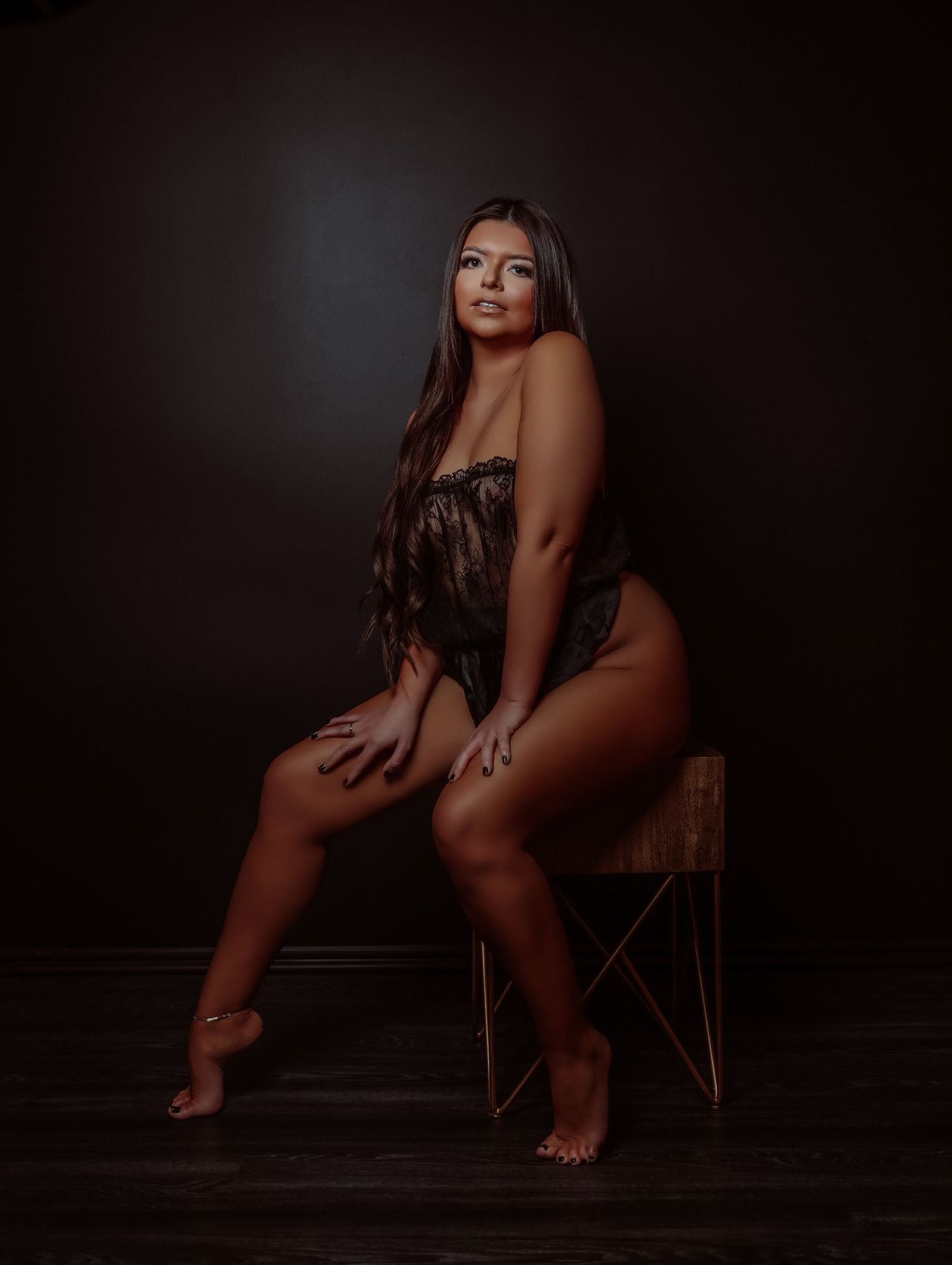 Boudoir portrait of beautiful young woman posing in strapless black lace lingerie with long brown hair for photoshoot with Boudoir by Bri