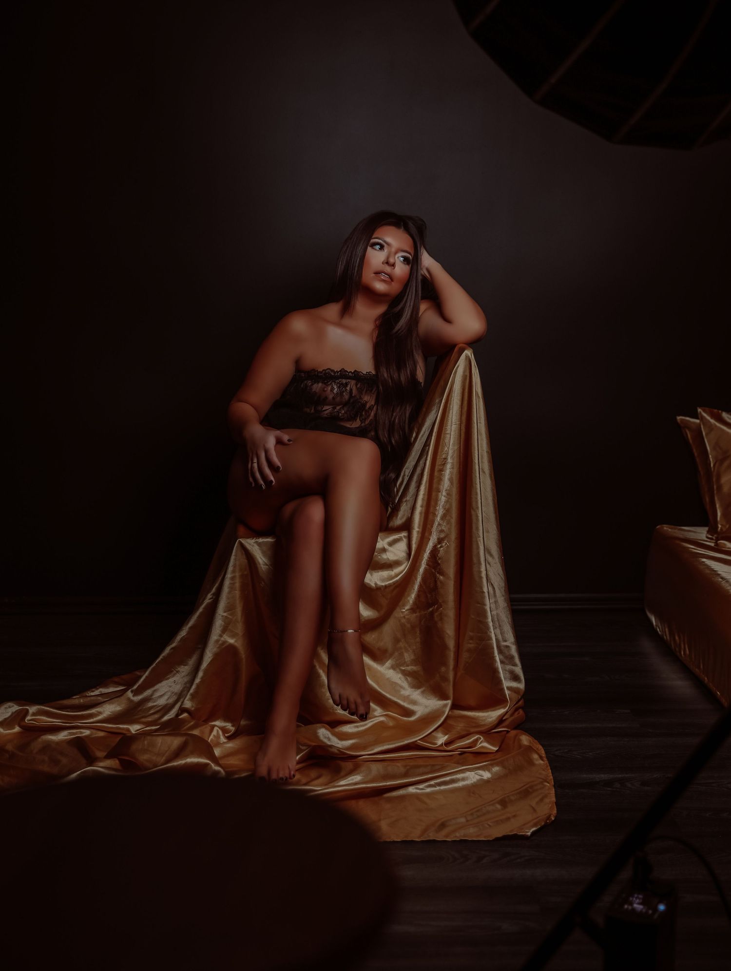 Boudoir portrait of beautiful woman in black lingerie posing with gold satin sheet on chair photoshoot with Boudoir by Bri in Saint Louis