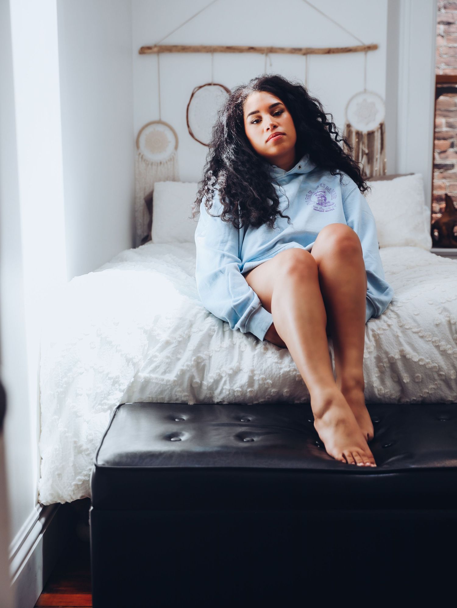 Beautiful woman posing in cozy blue hoodie and underwear in white bedroom for photoshoot with Boudoir by Bri in Saint Louis