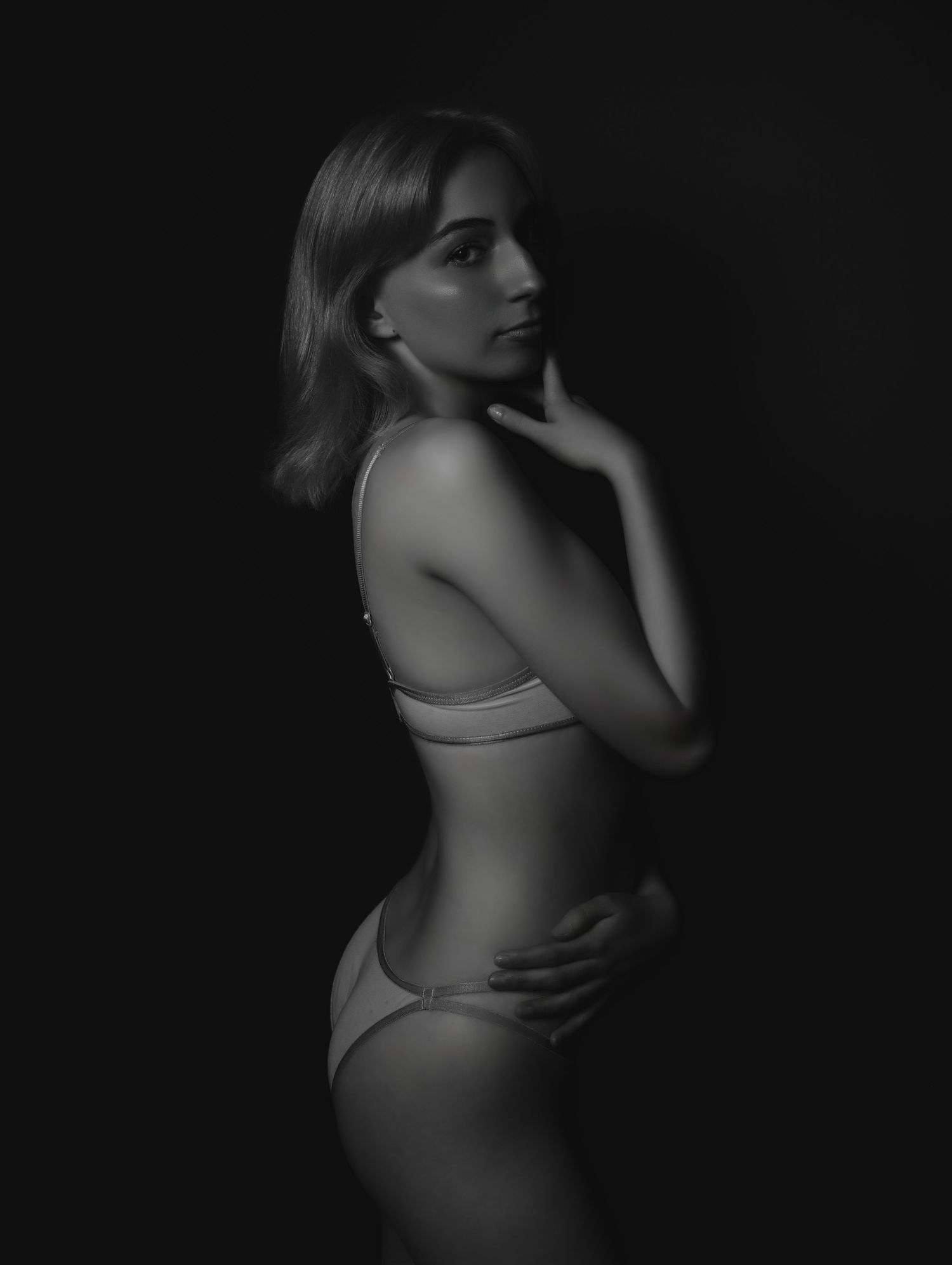 Boudoir portrait of beautiful young woman posing in lingerie in black and white for photoshoot with Boudoir by Bri in Saint Louis