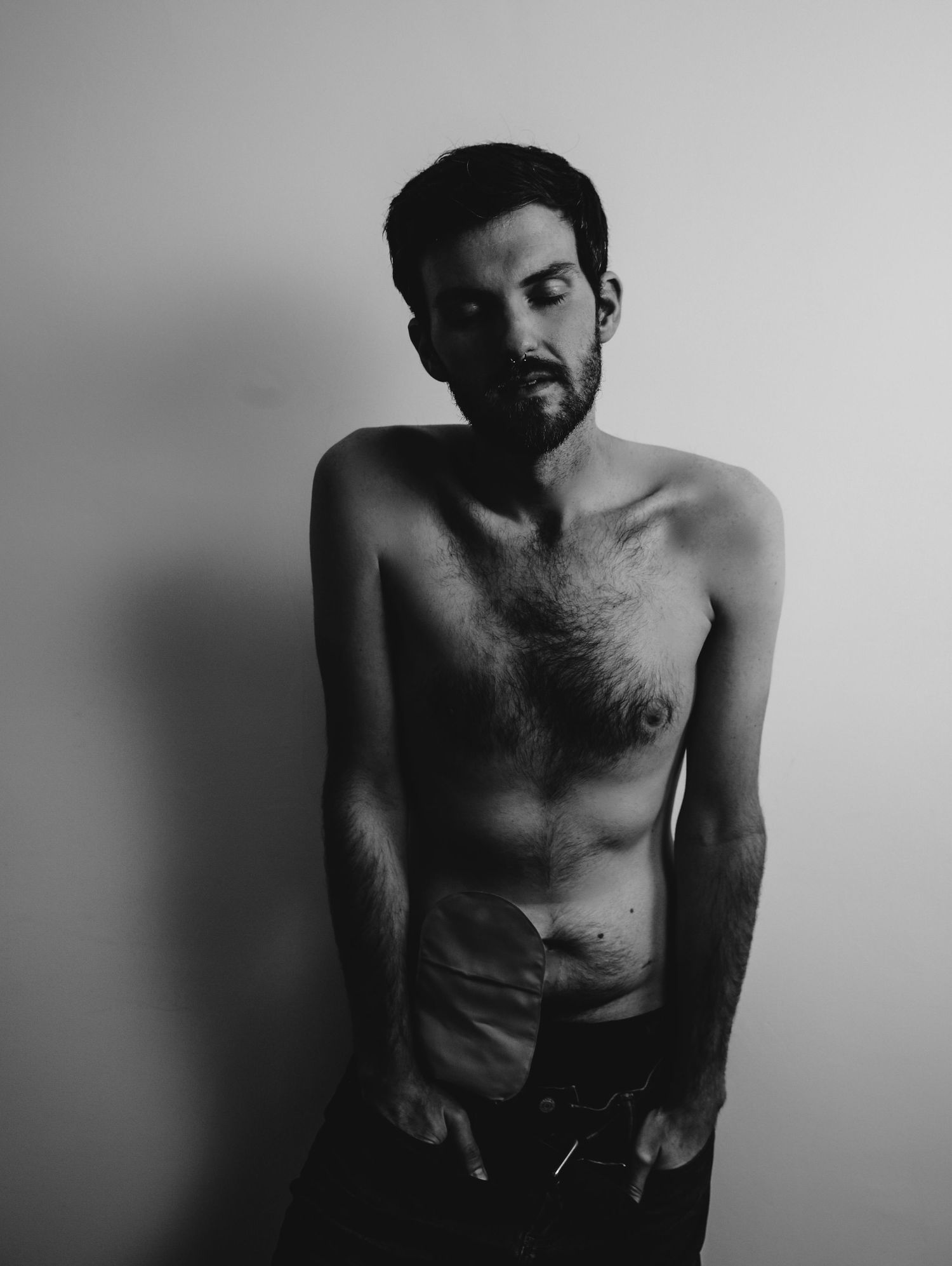 Boudoir portrait of beautiful young man in dramatic lighting with hands in pockets for photoshoot with Boudoir by Bri in Saint Louis