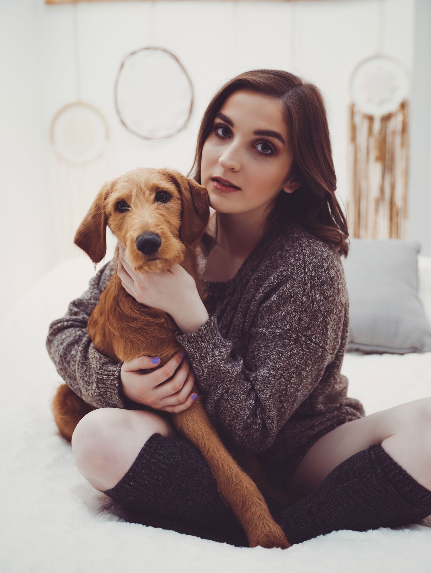 Boudoir portrait of beautiful young woman holding large brown puppy cuddling in white bedroom for photoshoot with Boudoir by Bri St. Louis