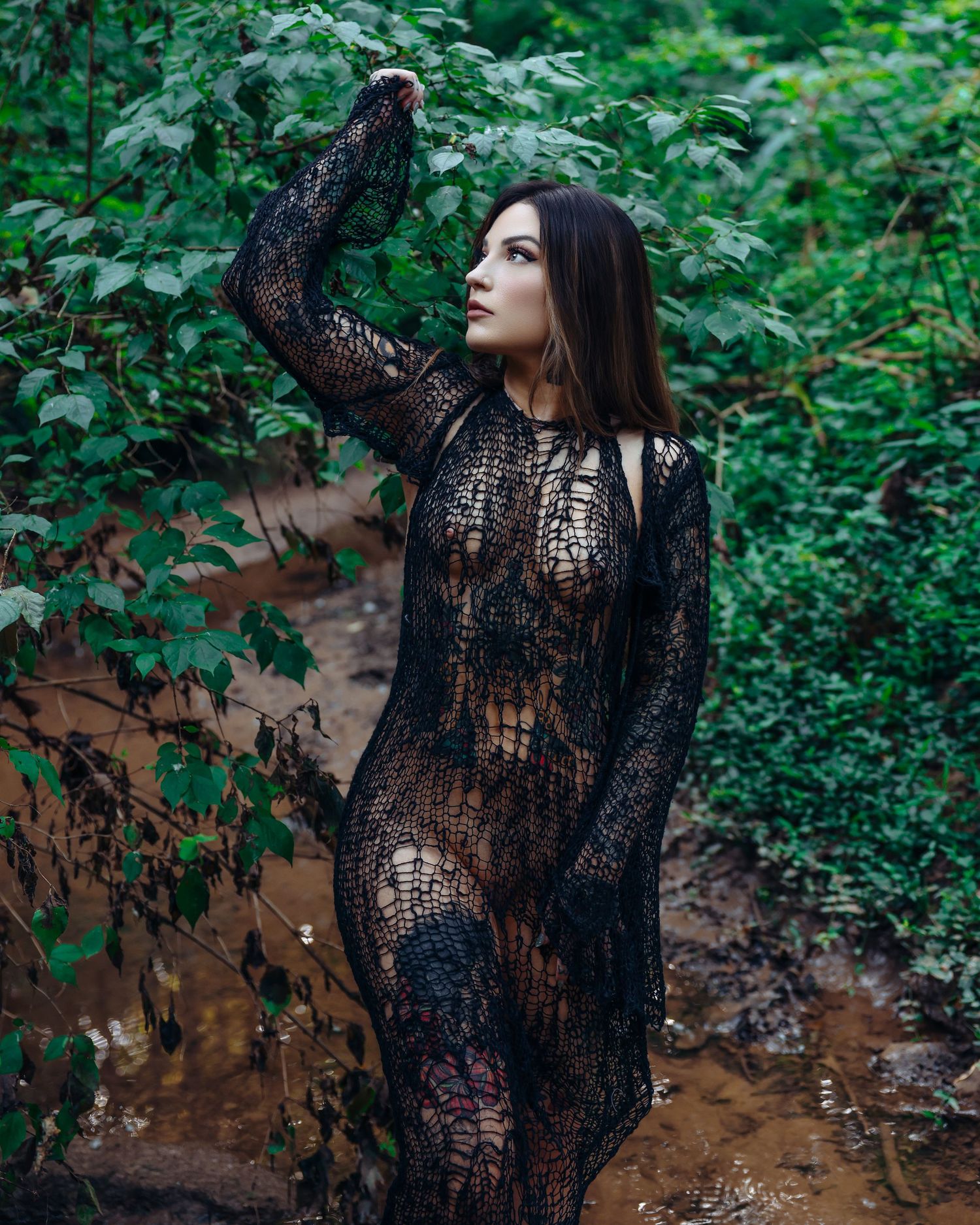 Beautiful tattooed woman posing in woods creek wearing black dress for outdoor boudoir session photoshoot with Boudoir by Bri in Saint Louis