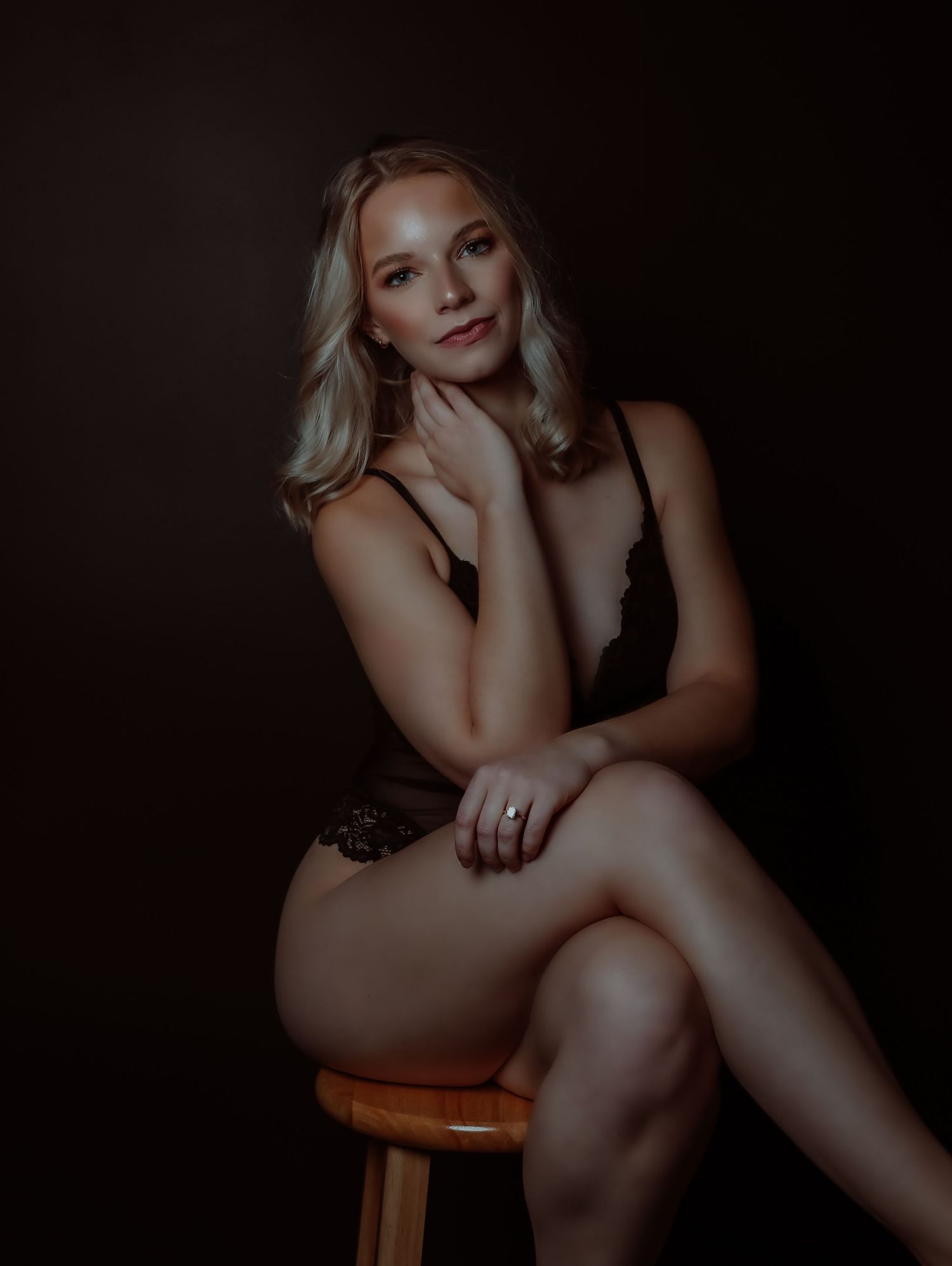 Dramatic portrait of beautiful young woman on stool wearing black lingerie and posing for photoshoot with Boudoir by Bri Saint Louis