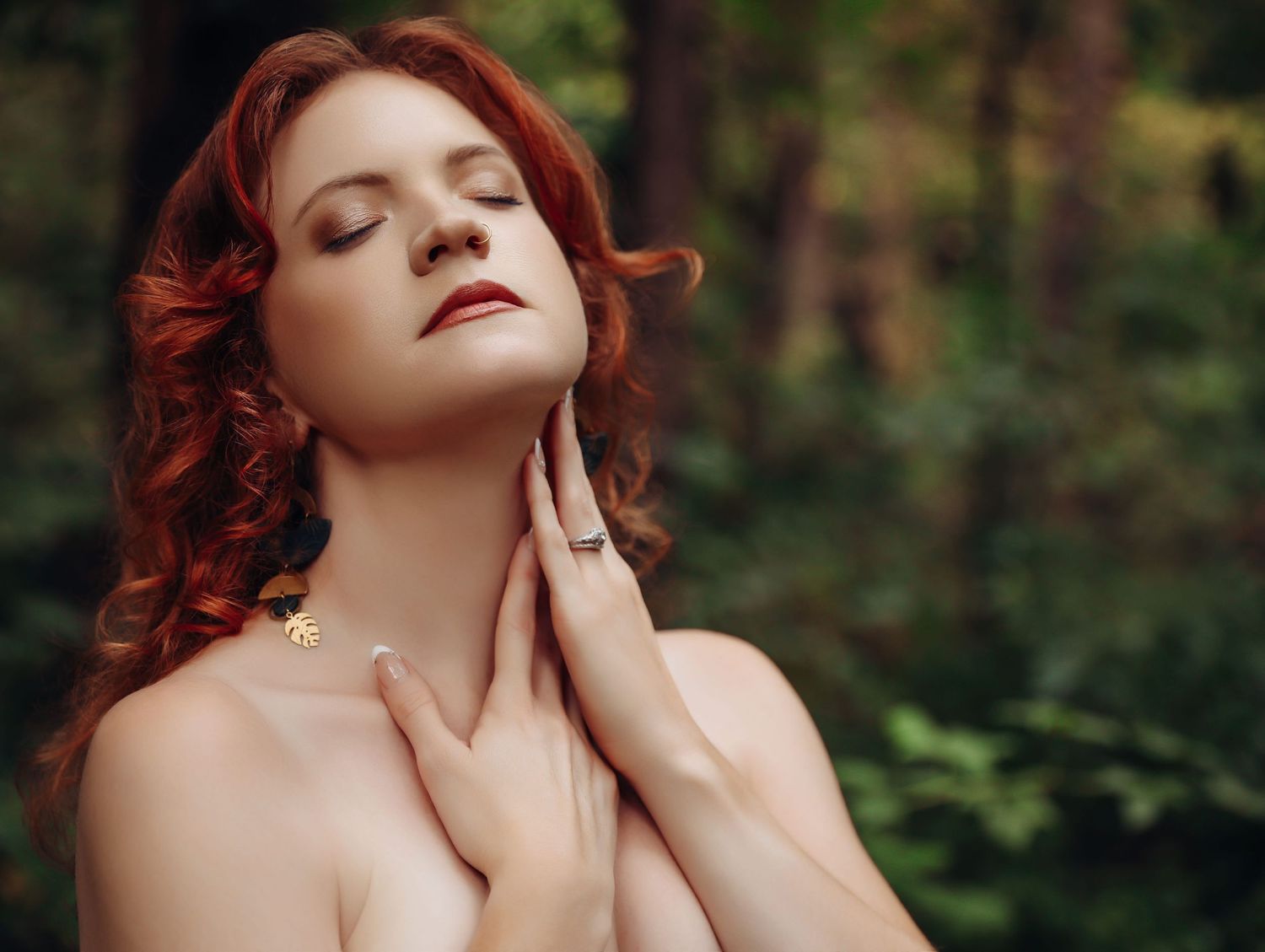 Beautiful woman with red curly hair posing in woods with eyes closed for photoshoot with Boudoir by Bri in Saint Louis