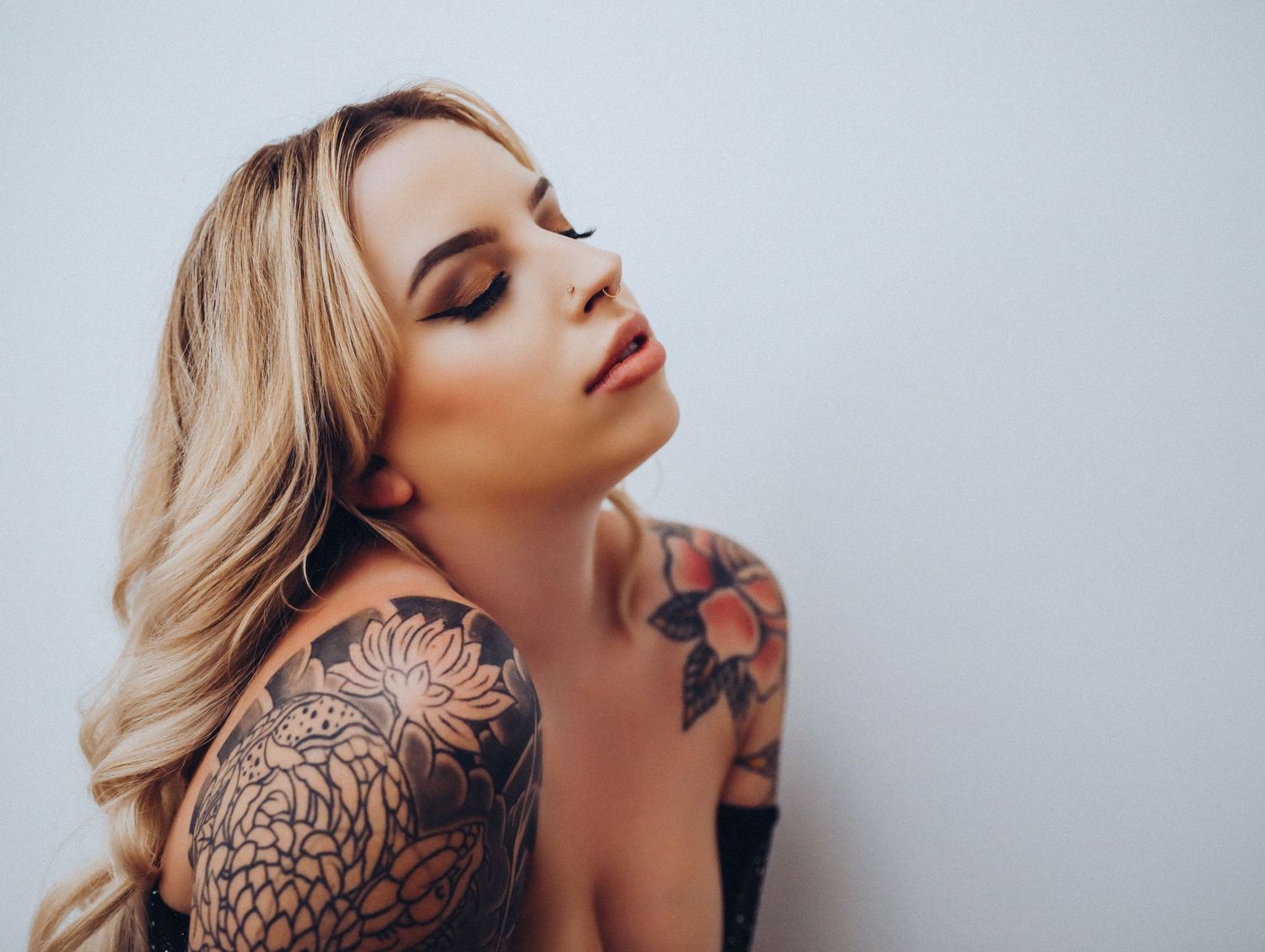 Dramatic portrait of beautiful young blonde tattooed woman headshot with eyes closed for photoshoot with Boudoir by Bri Saint Louis