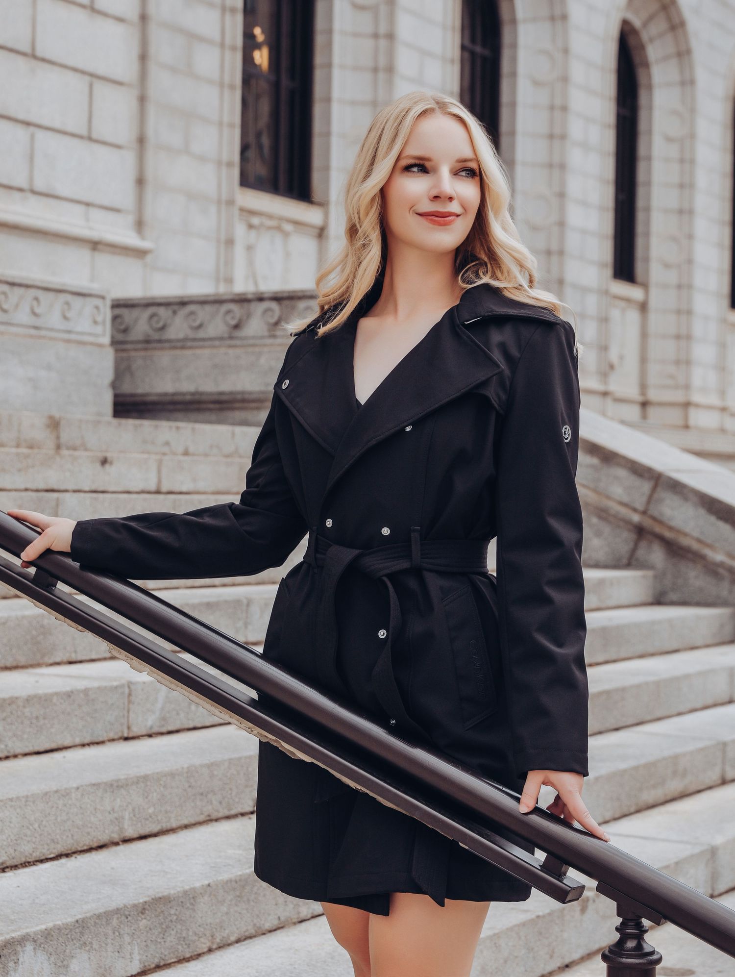 Gorgeous blonde woman posing in front of marble steps in black trench coat with lingerie underneath for Boudoir by Bri in Saint Louis
