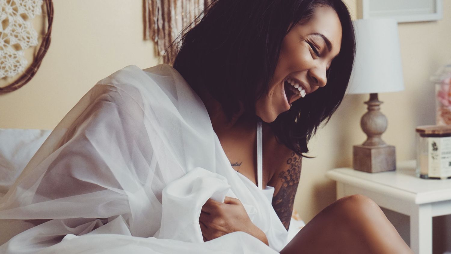 Boudoir portrait of happy beautiful young woman smiling and laughing in bedroom for photoshoot with Boudoir by Bri in Saint Louis