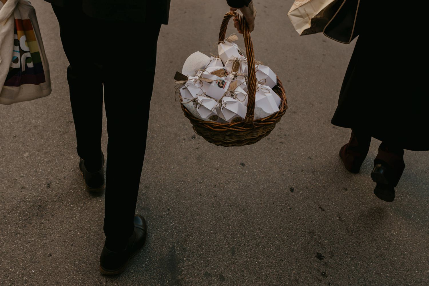 Person carrying a wicker basket filled with white folded napkins while walking outdoors.