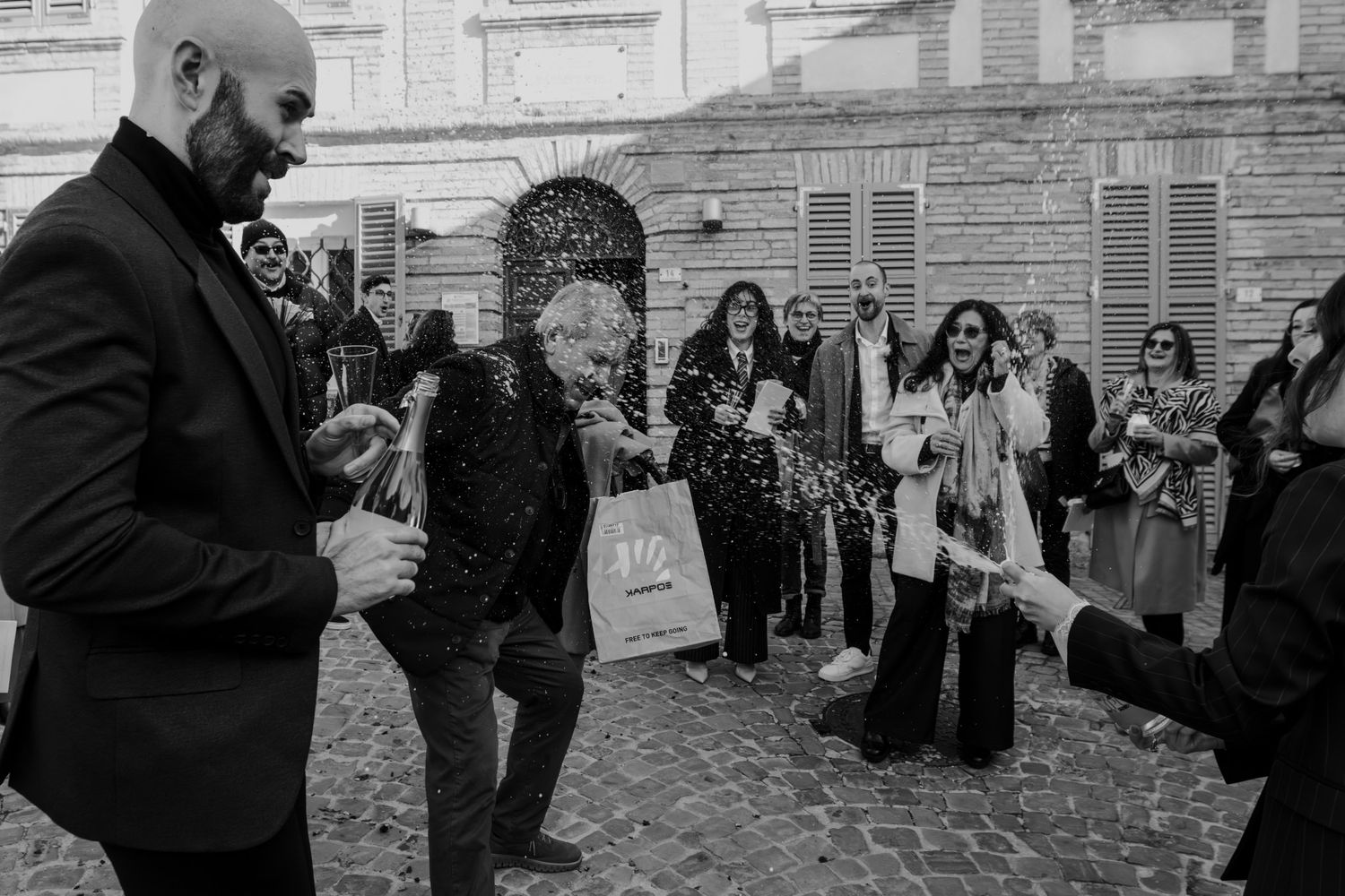 Black and white photo of wedding guest being sprayed with champagne