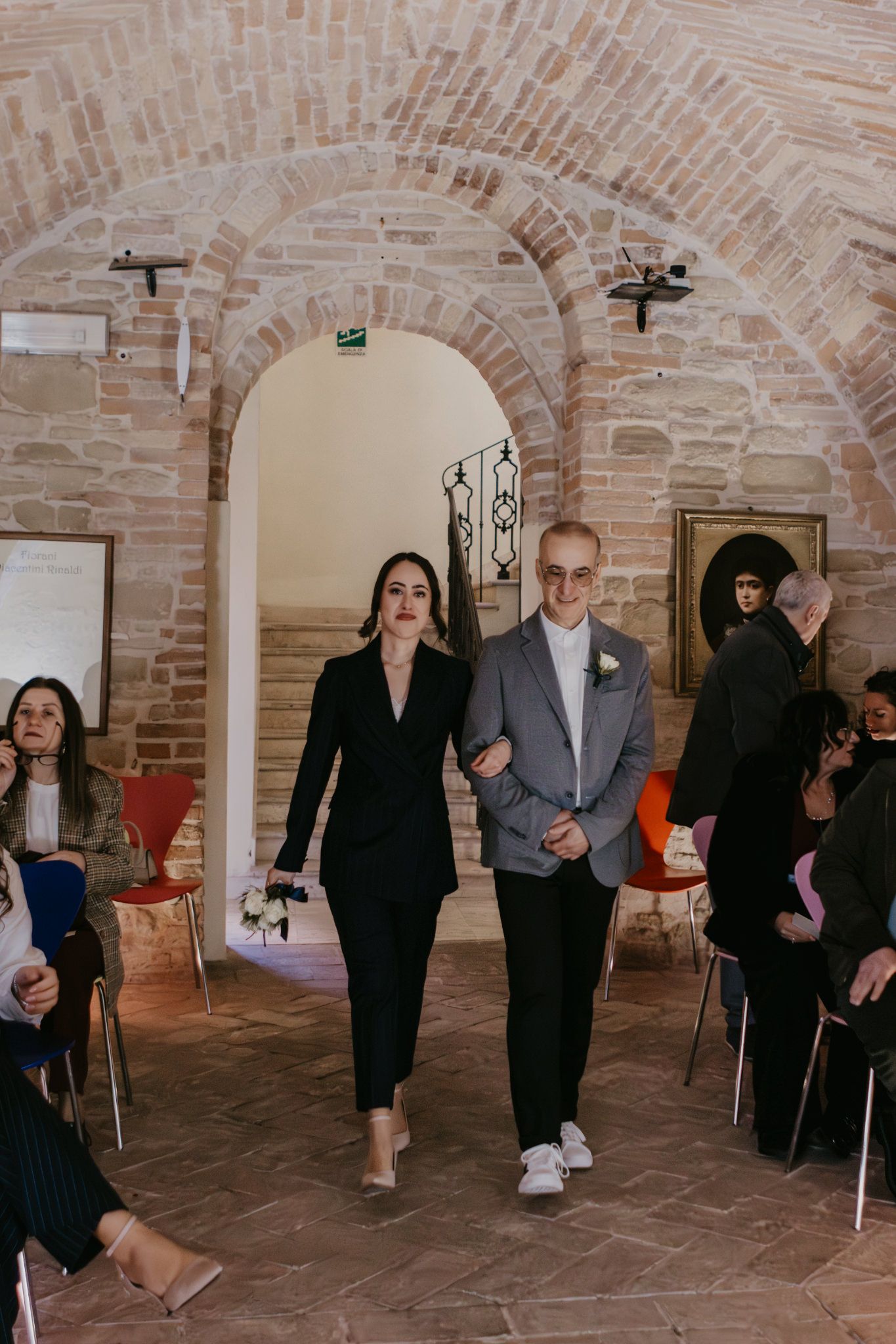 Couple walks down the aisle in a rustic brick venue during an elegant wedding ceremony.