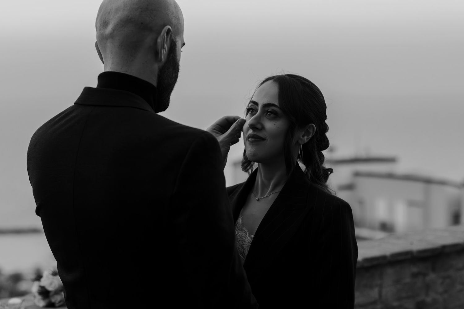 Black and white photo of a couple sharing a tender moment outdoors, man gently touching womans face.
