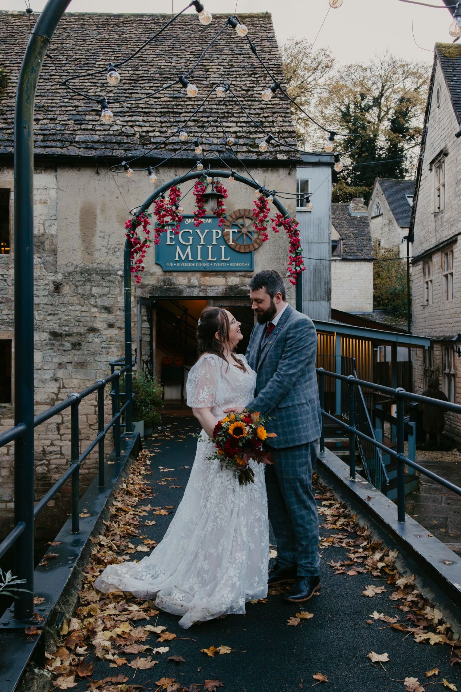 Bride and groom share a romantic moment on a bridge outside Egypt Mill venue, surrounded by autumn leaves.