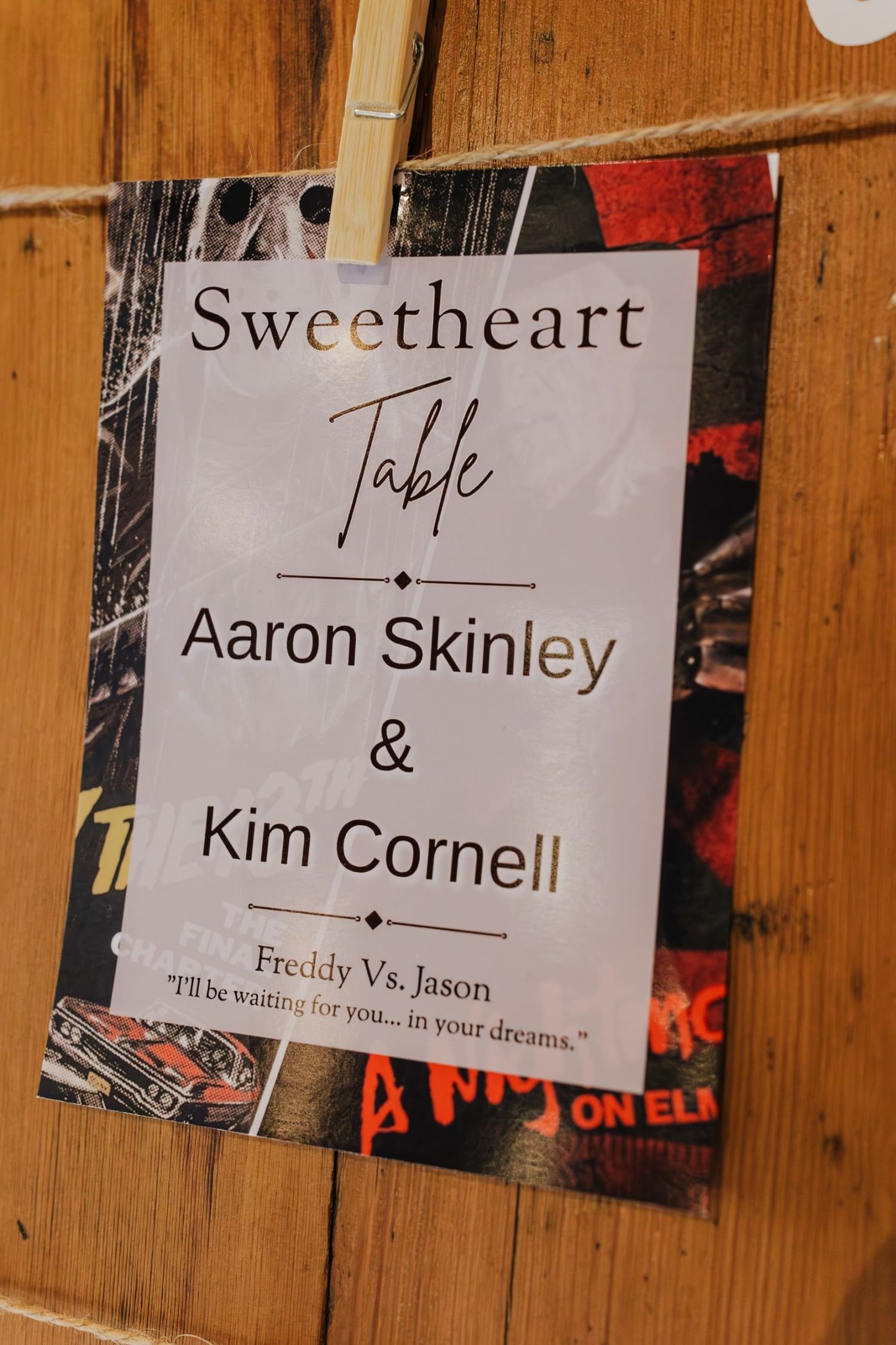 Sweetheart Table sign for wedding couple with a Freddy Vs. Jason theme, clipped to a wooden board.