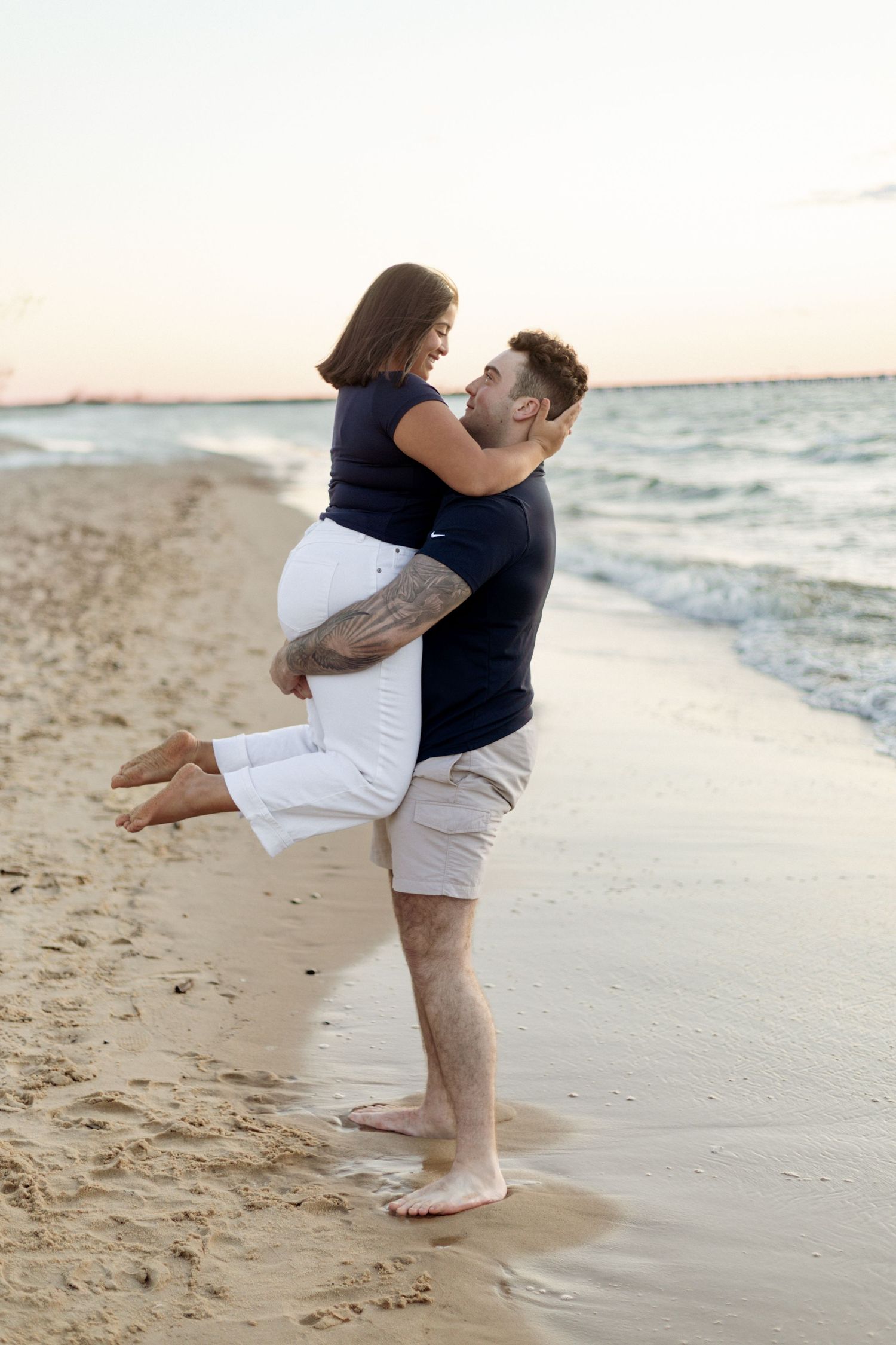 Couple sharing playful moment on sandy beach during sunset.