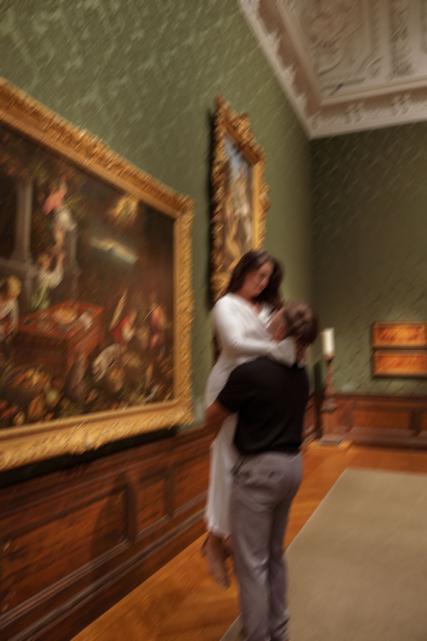 Motion-blurred sequence of a person walking through an art gallery with green walls and ornate gold-framed paintings.