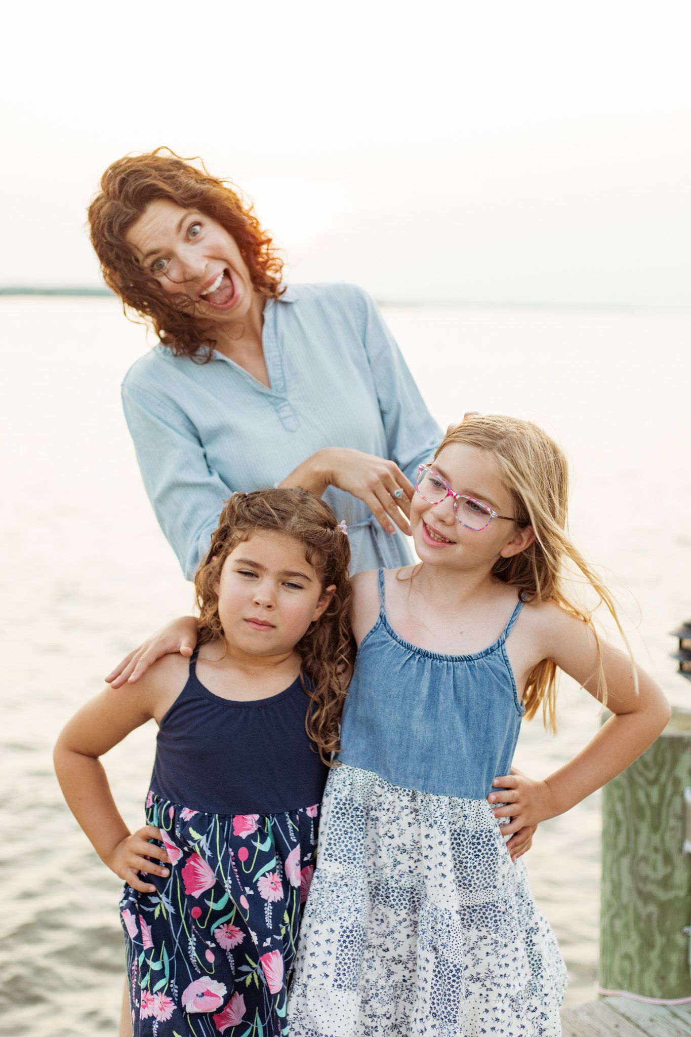 A joyful family moment captured outdoors with two young girls and their parent by the water.