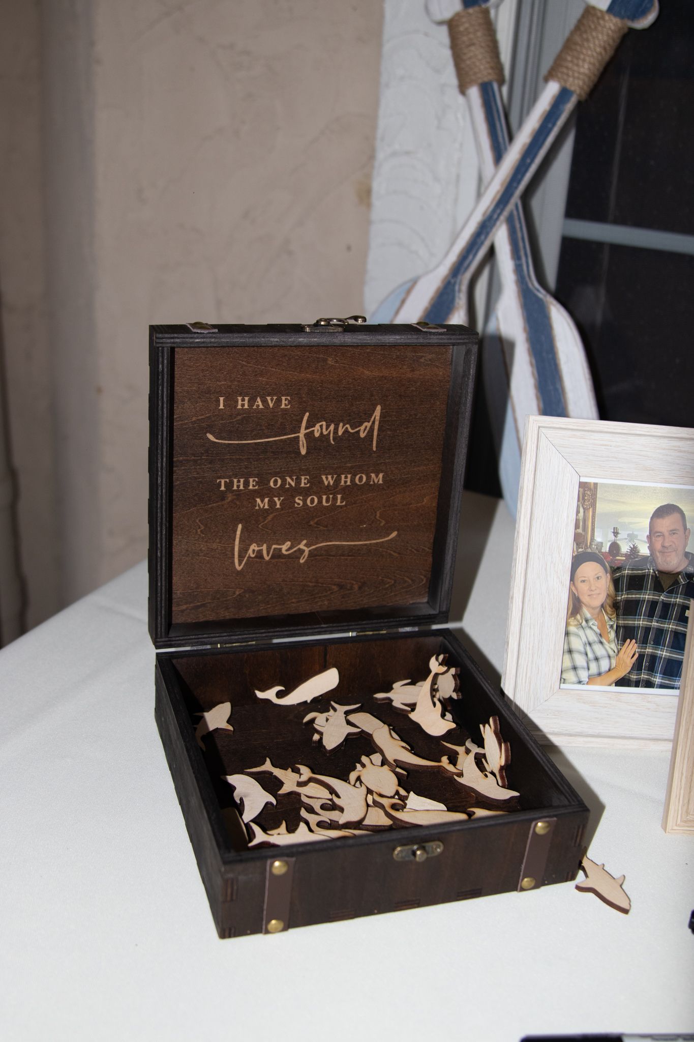 Wooden wedding keepsake box engraved with 'I Have Found The One Whom My Soul Loves' filled with heart cutouts.