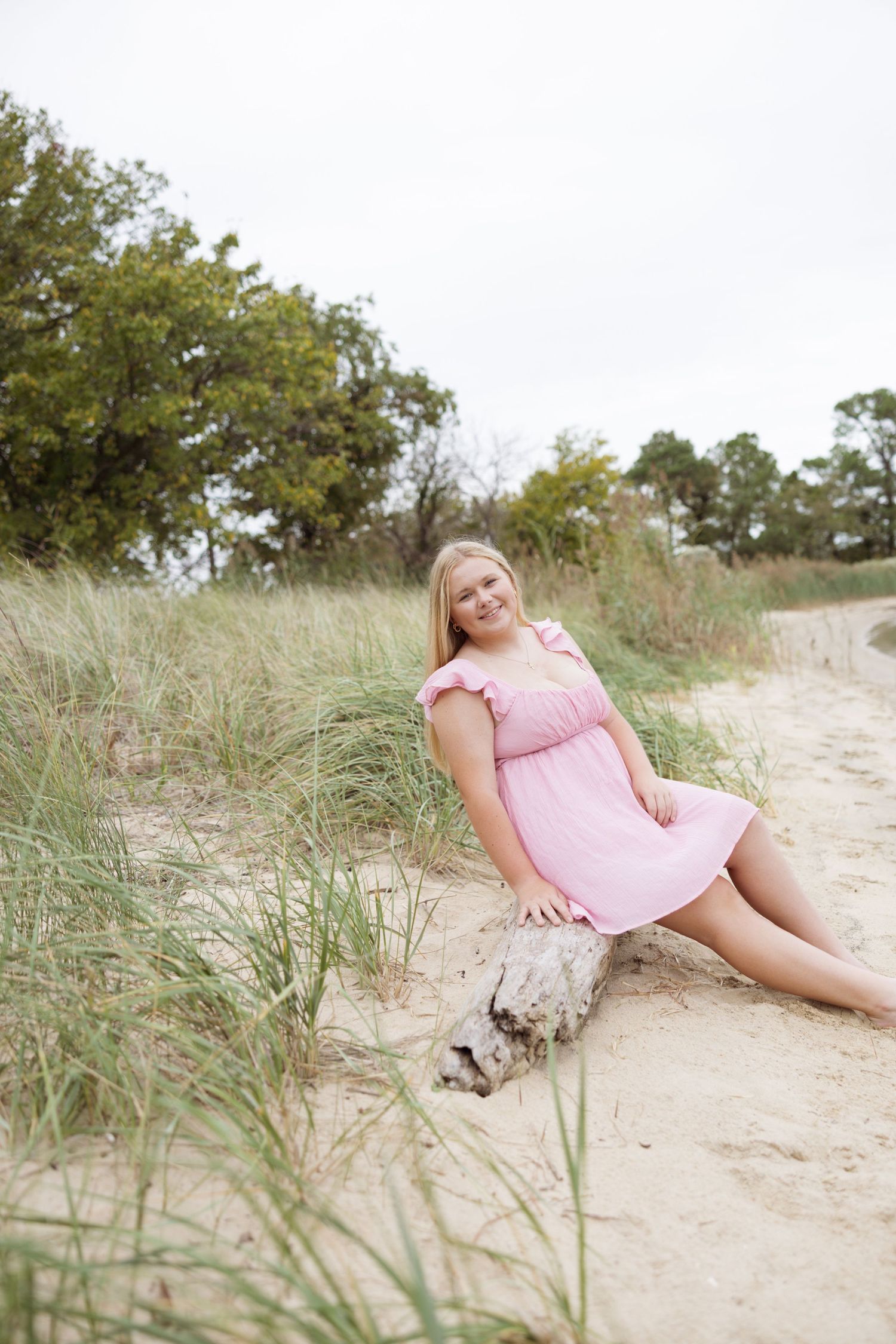 Four sequential photos show someone in a pink dress reclining on a sandy beach path surrounded by beach grass and dunes.