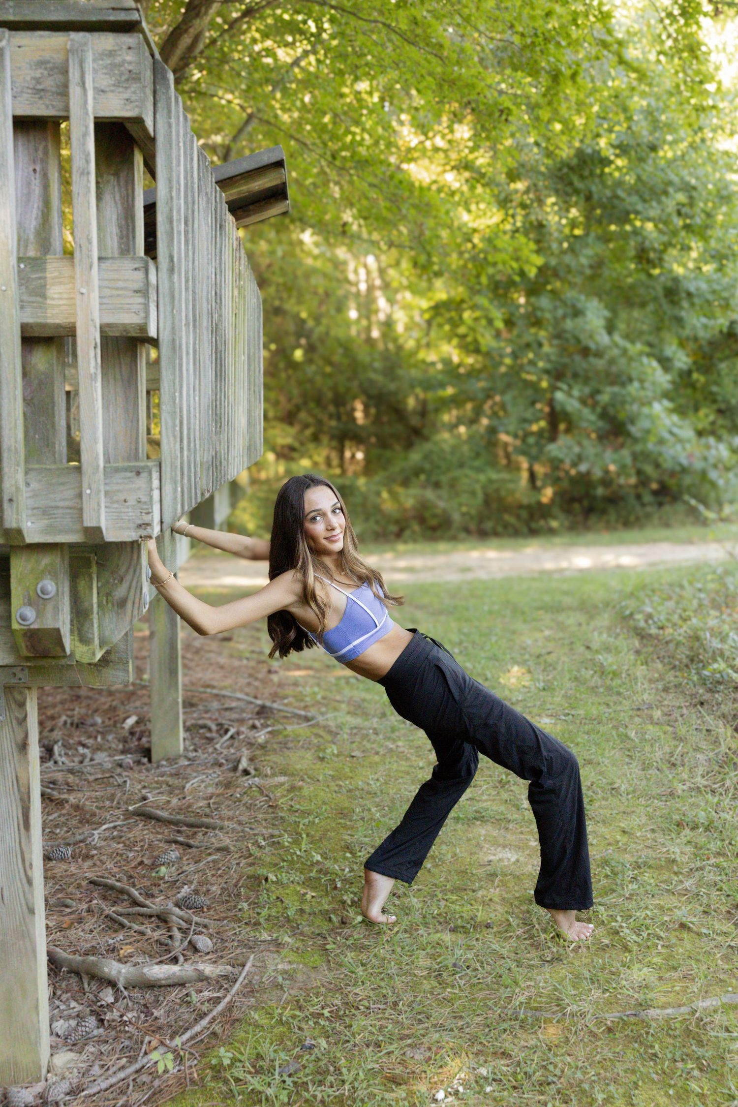 Three artistic dance poses captured in sequence against a rustic wooden backdrop in a natural outdoor setting.
