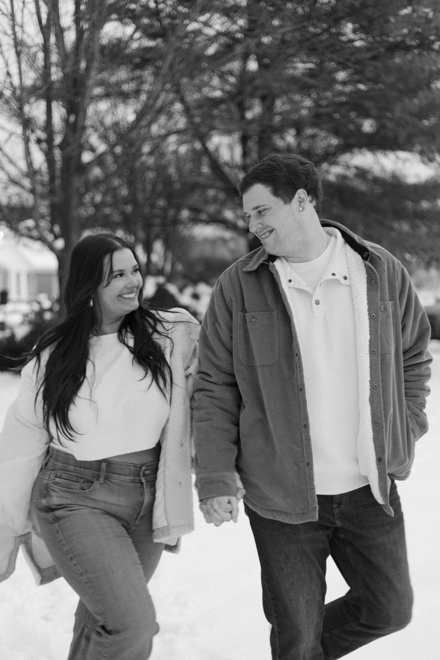 Black and white portrait of couple walking together in winter wonderland.
