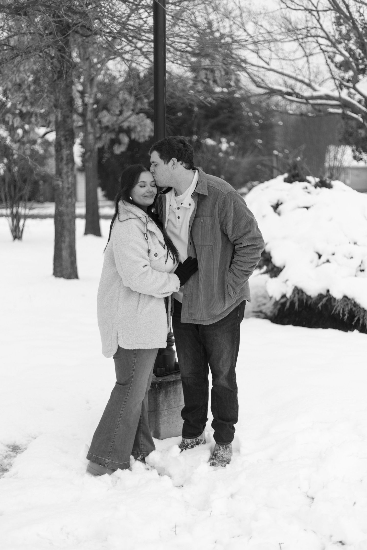 Romantic black and white winter portrait of couple in snowfall.