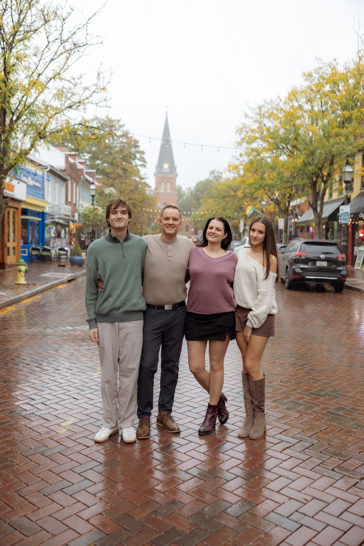 Group walking together on wet brick sidewalk in autumn weather wearing coordinated neutral colored outfits.