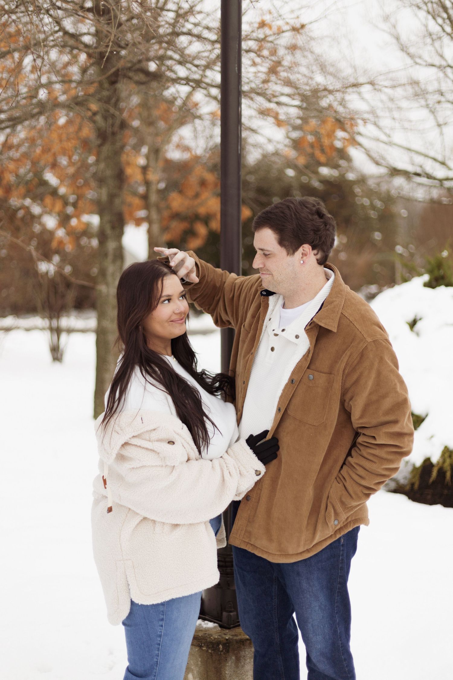 Couple sharing an intimate winter moment against snowy backdrop.