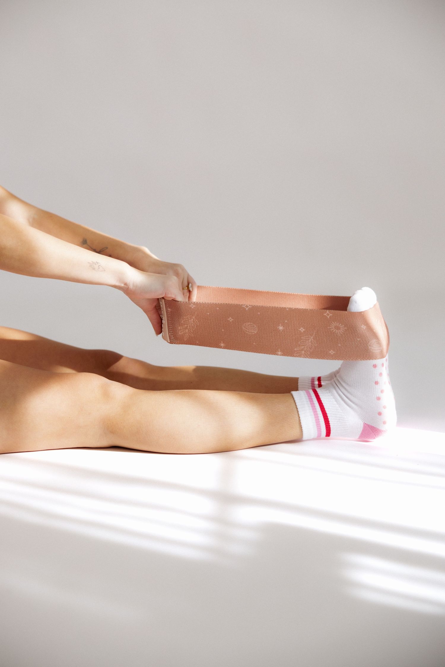 Series of hands applying kinesiology tape to a leg in a therapeutic sequence against a white background.