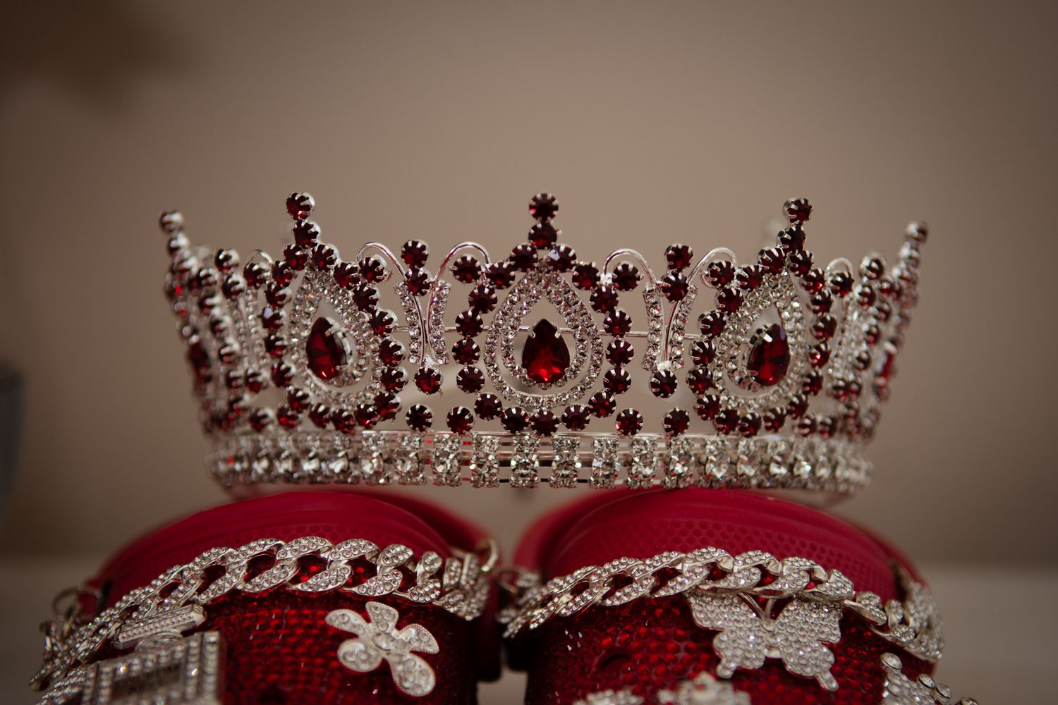 Elegant red and silver rhinestone quinceañera crown displayed on matching red embroidered shoes.