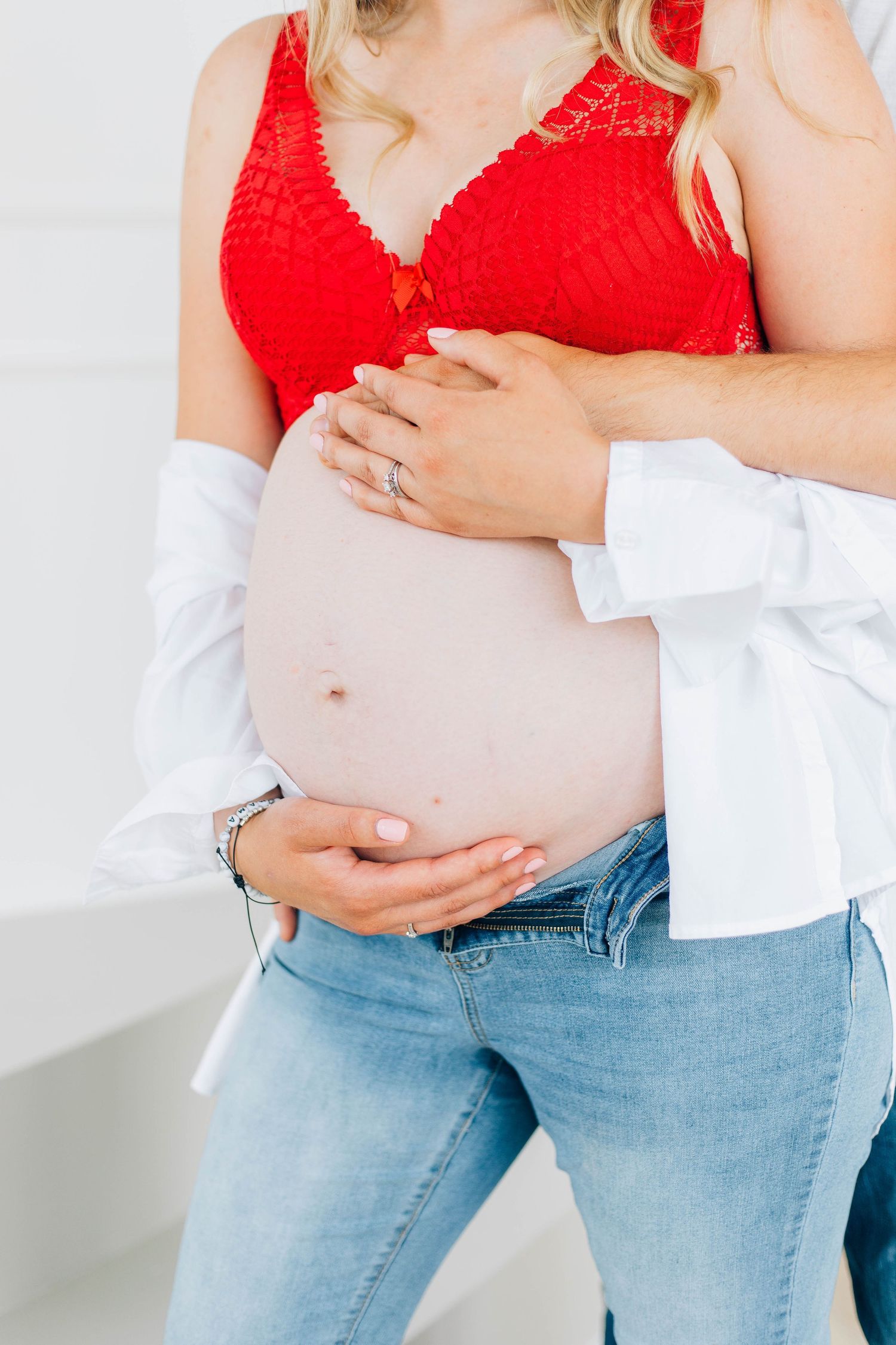 Close-up of pregnant belly with couple's hands cradling baby bump.