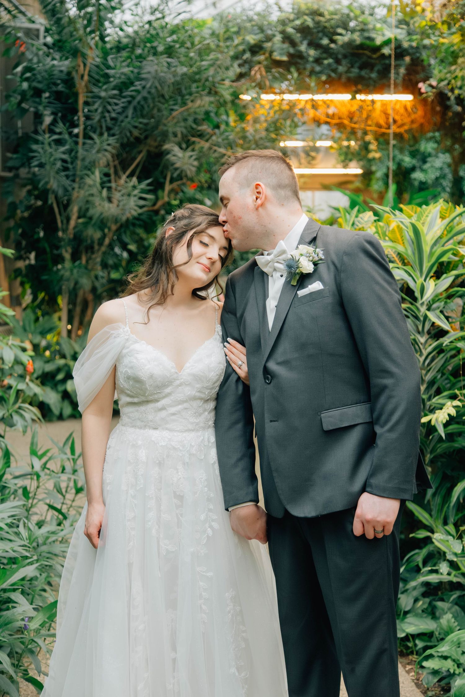 Groom kisses bride on the forehead at the Butterfly Conservatory in Cambridge Ontario.