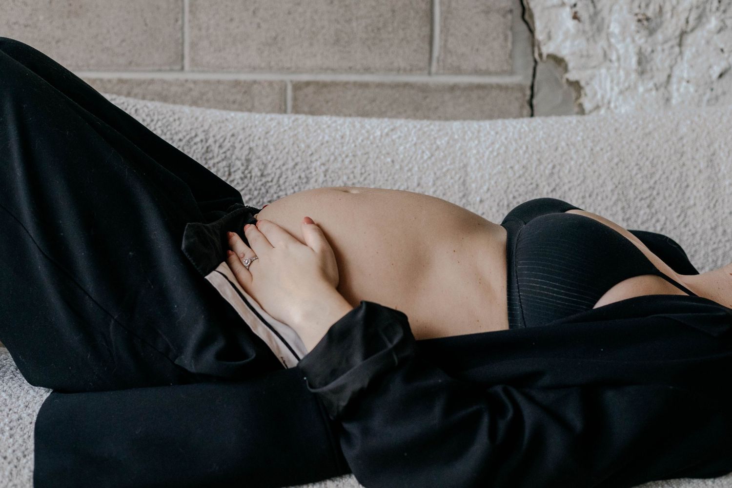 Pregnant woman lying on sofa showing bare baby bump during maternity session.