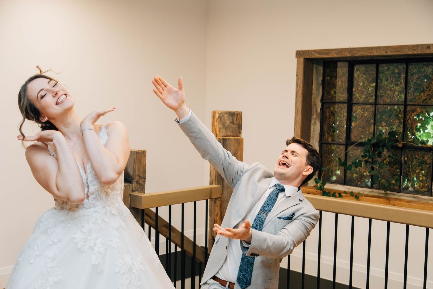 Bride and groom laughing and dancing together on a staircase during their wedding reception.