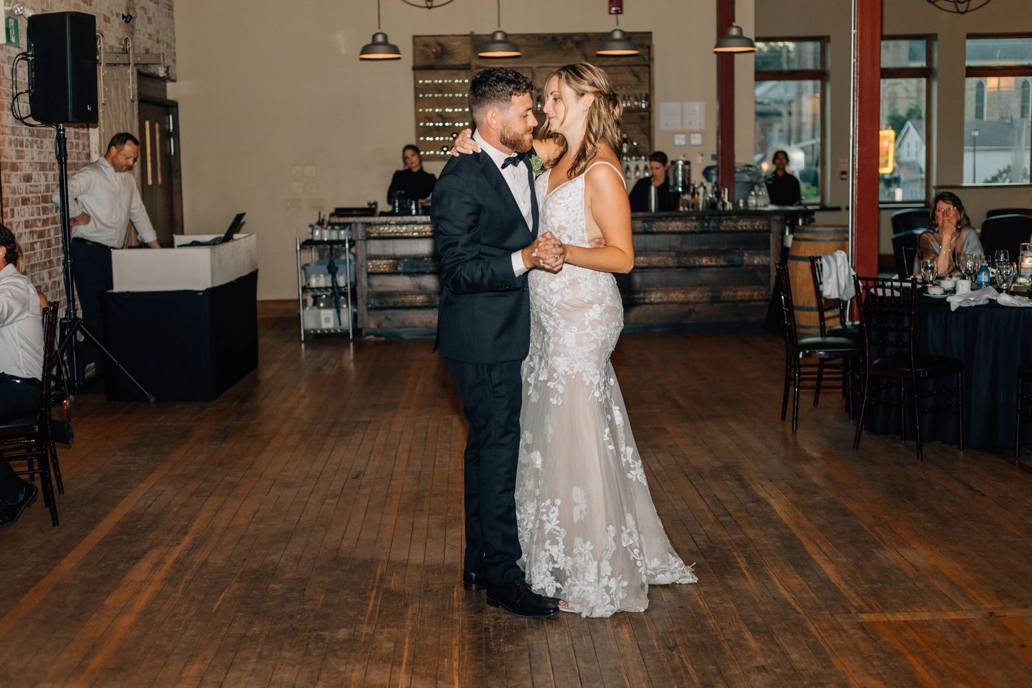 Bride and groom share romantic first dance on wooden floor at elegant wedding reception venue.
