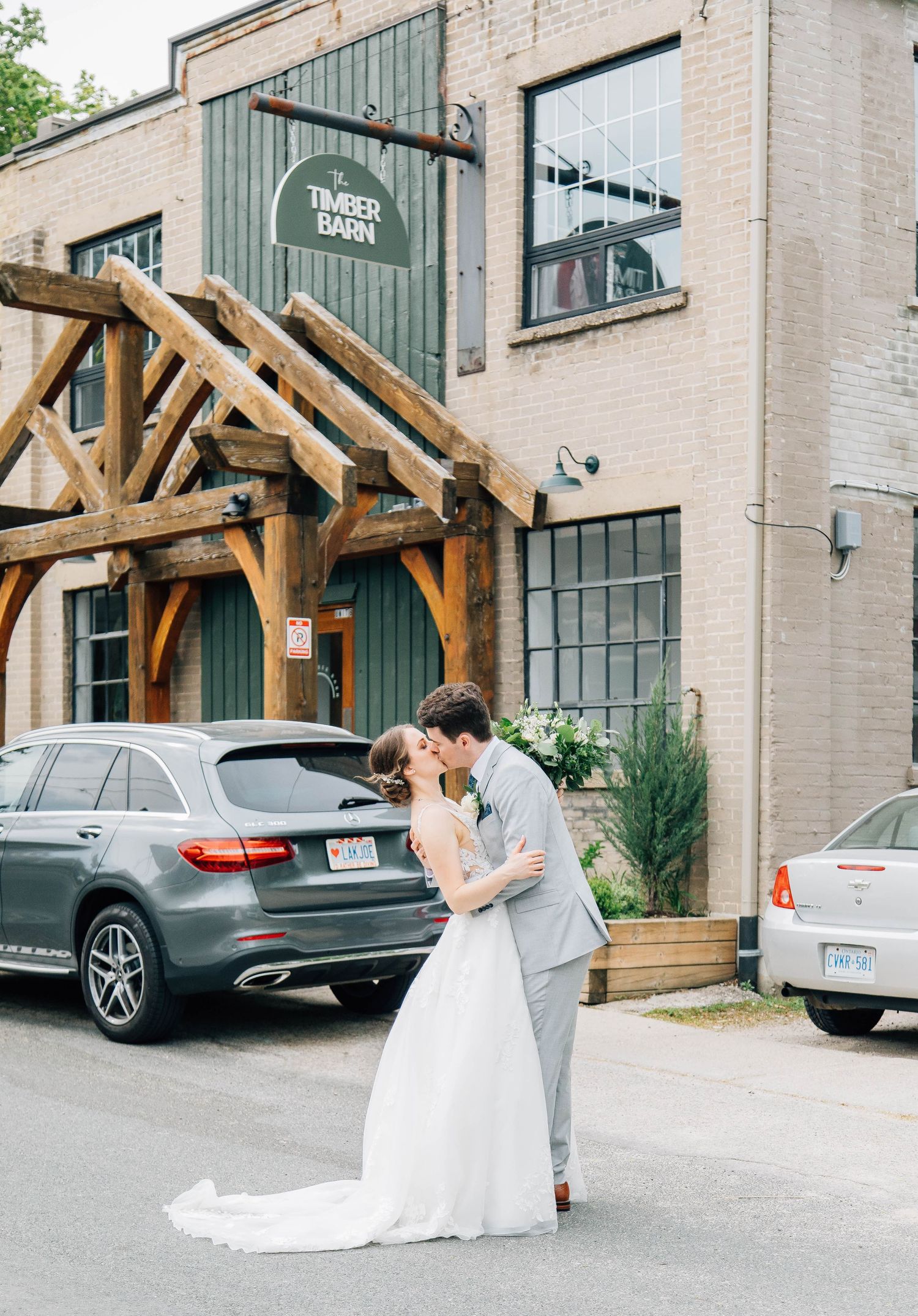 Bride and groom sharing a kiss outside the Timber Barn wedding venue on their special day.