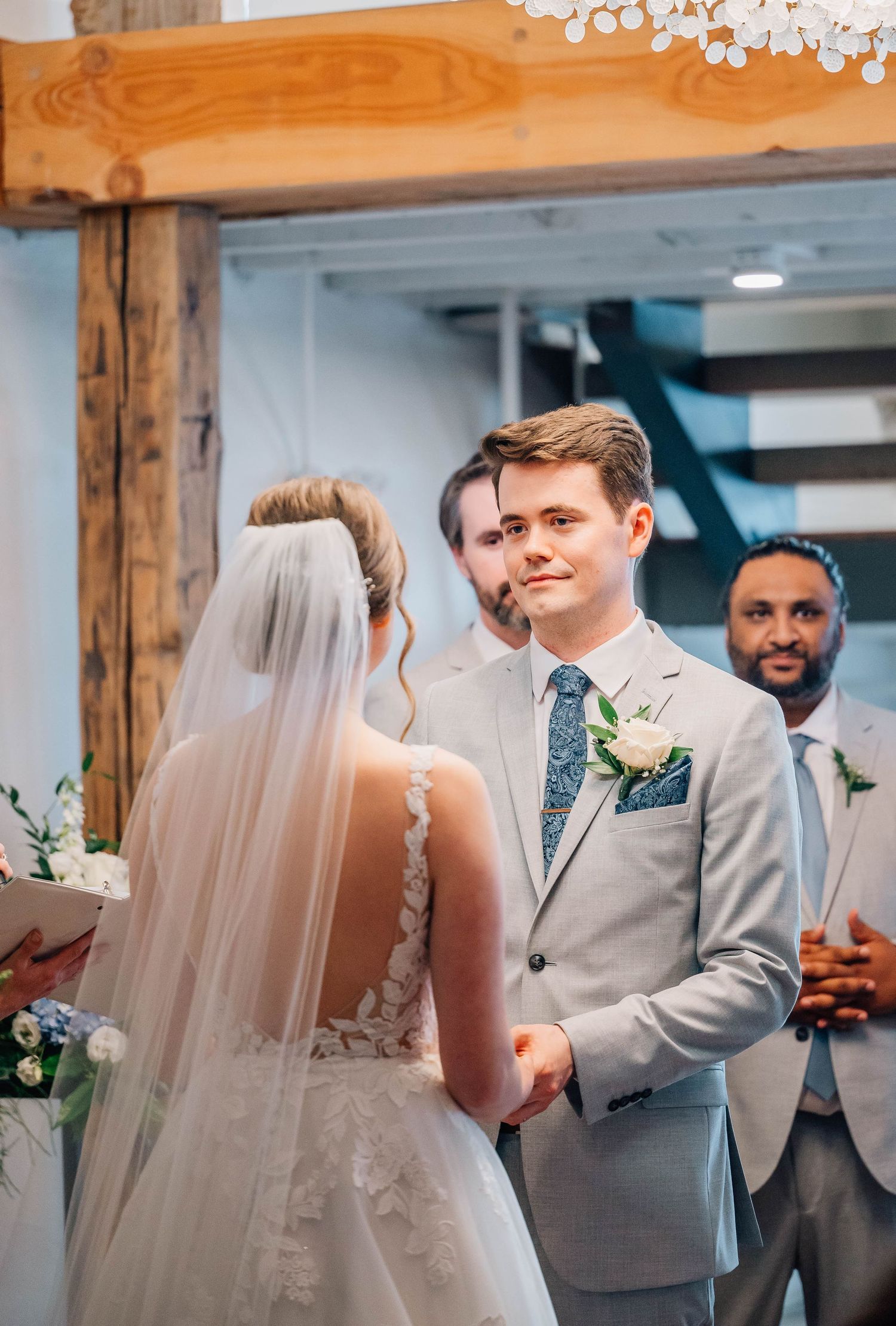 Groom smiling at bride during indoor wedding ceremony at the altar.