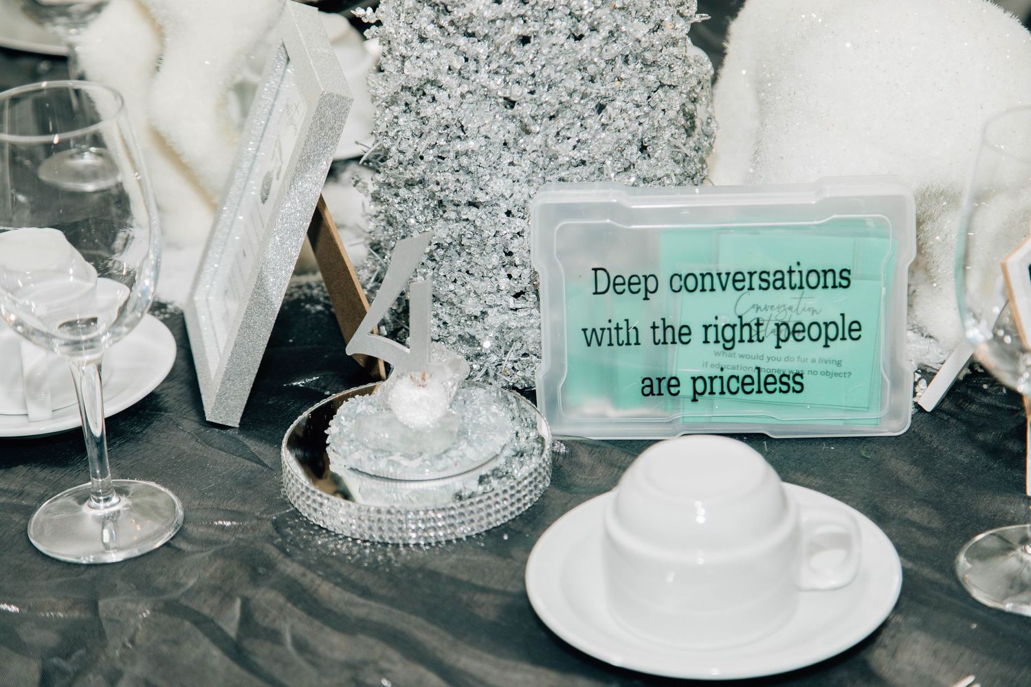 Elegant wedding table setting with a teal sign reading Deep conversations with the right people are priceless.