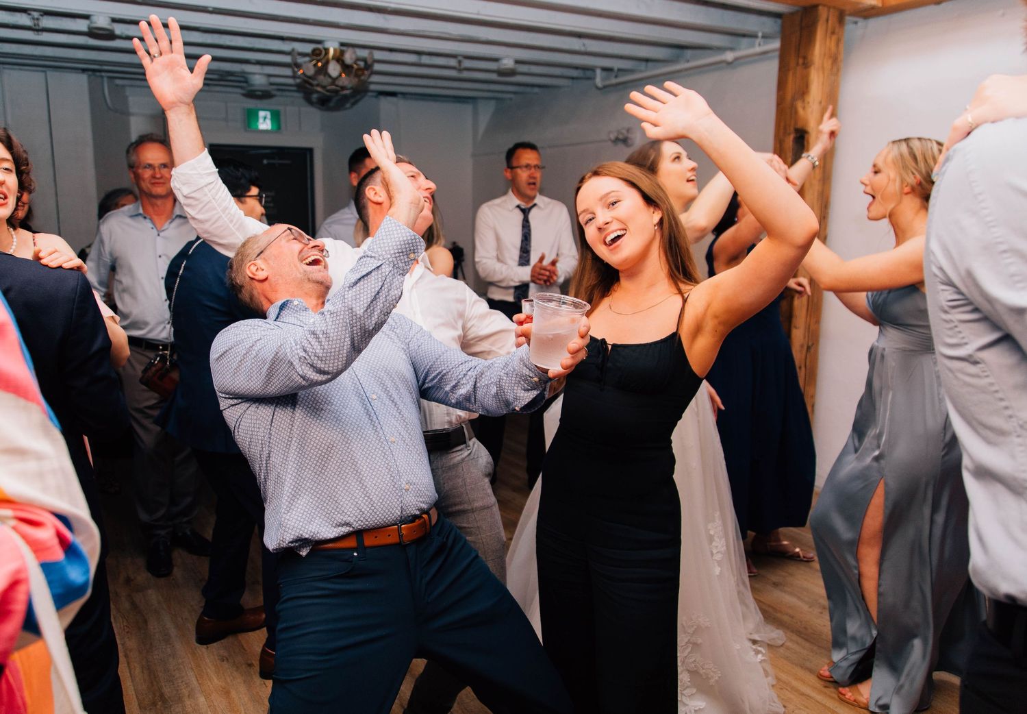Wedding guests dance energetically on the dance floor during a lively reception celebration.