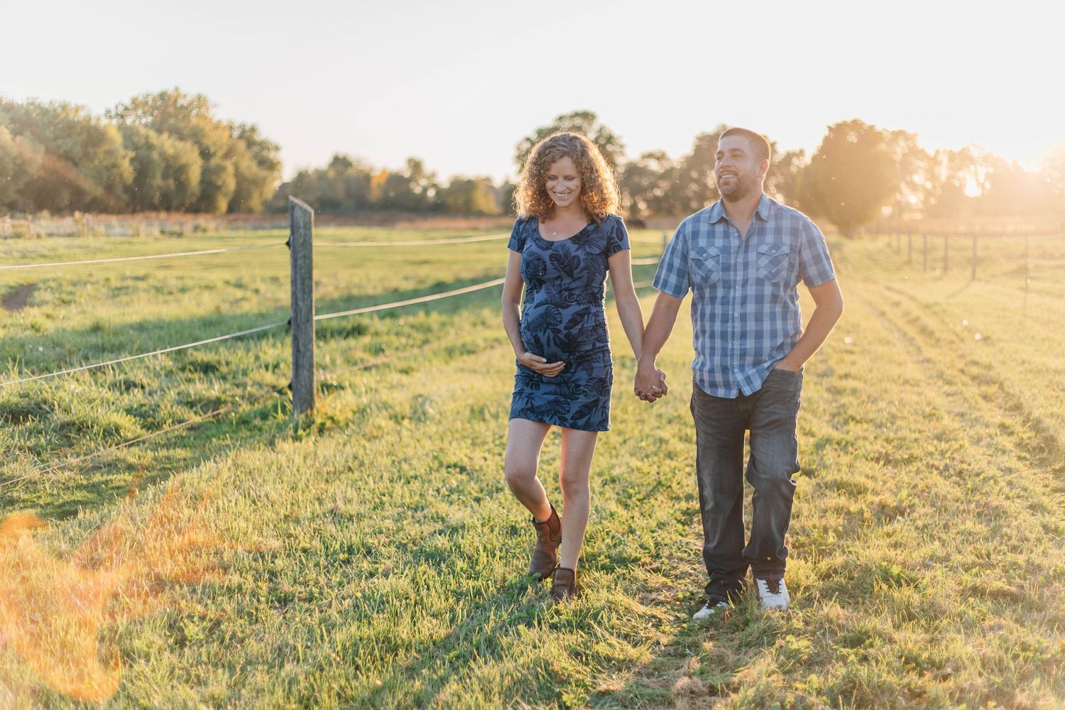 Expecting couple walking hand in hand on a farm in Thamesford Ontario