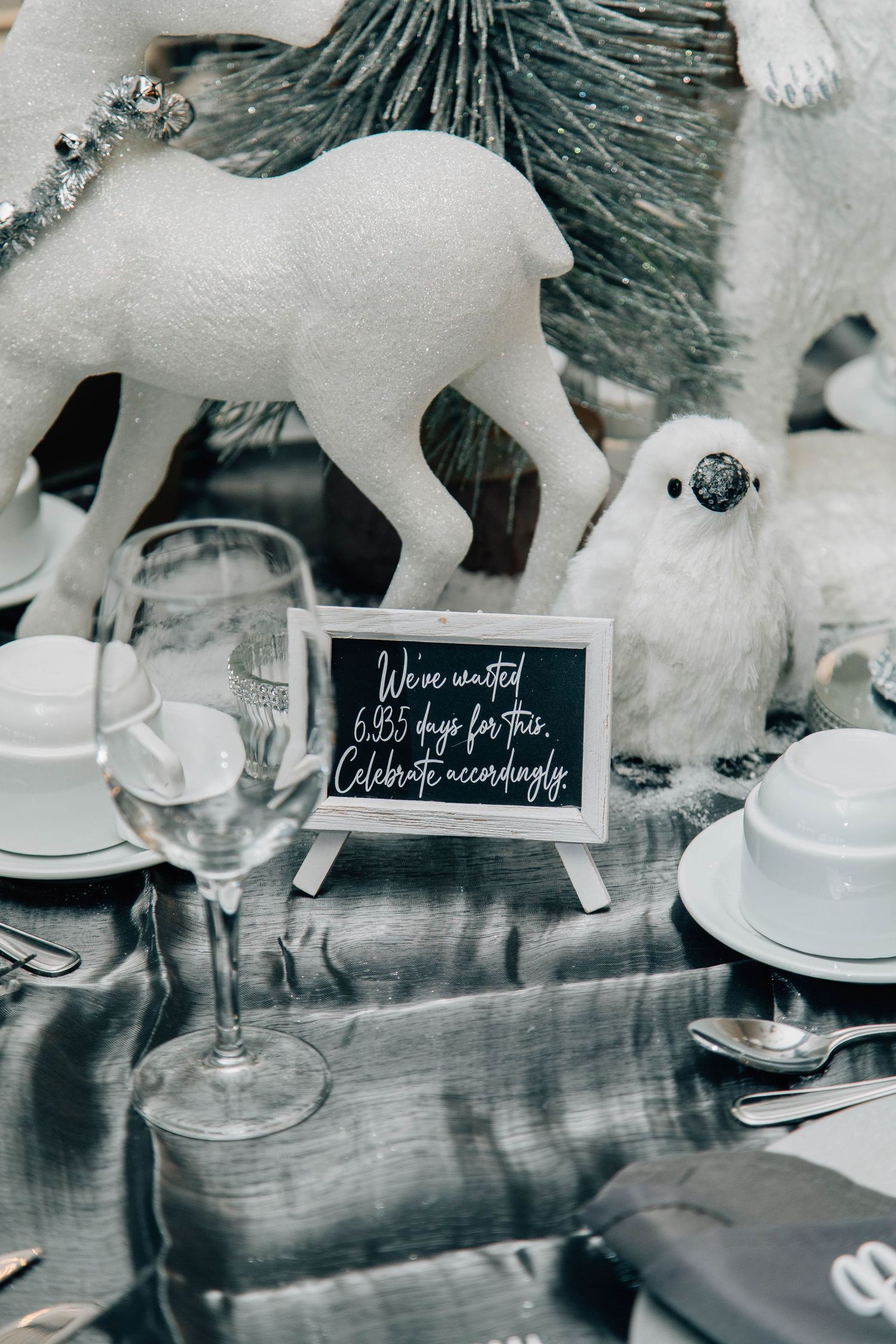 Winter wedding table decor featuring white animal figurines, a chalkboard sign, and elegant gray place settings.