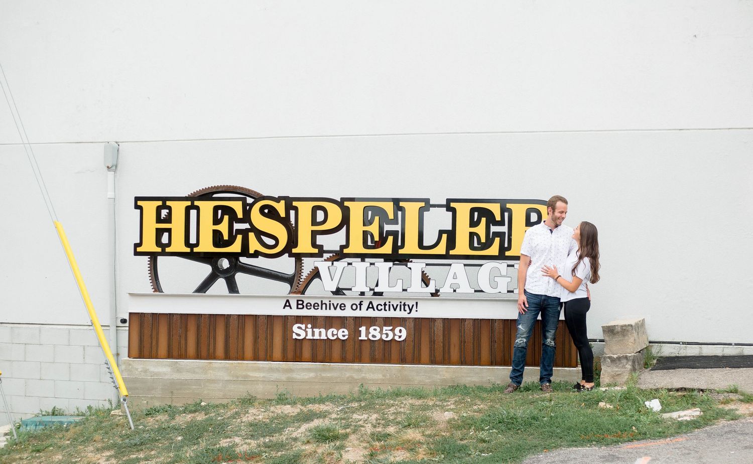 Couple standing together in front of Hespeler sign since 1859.