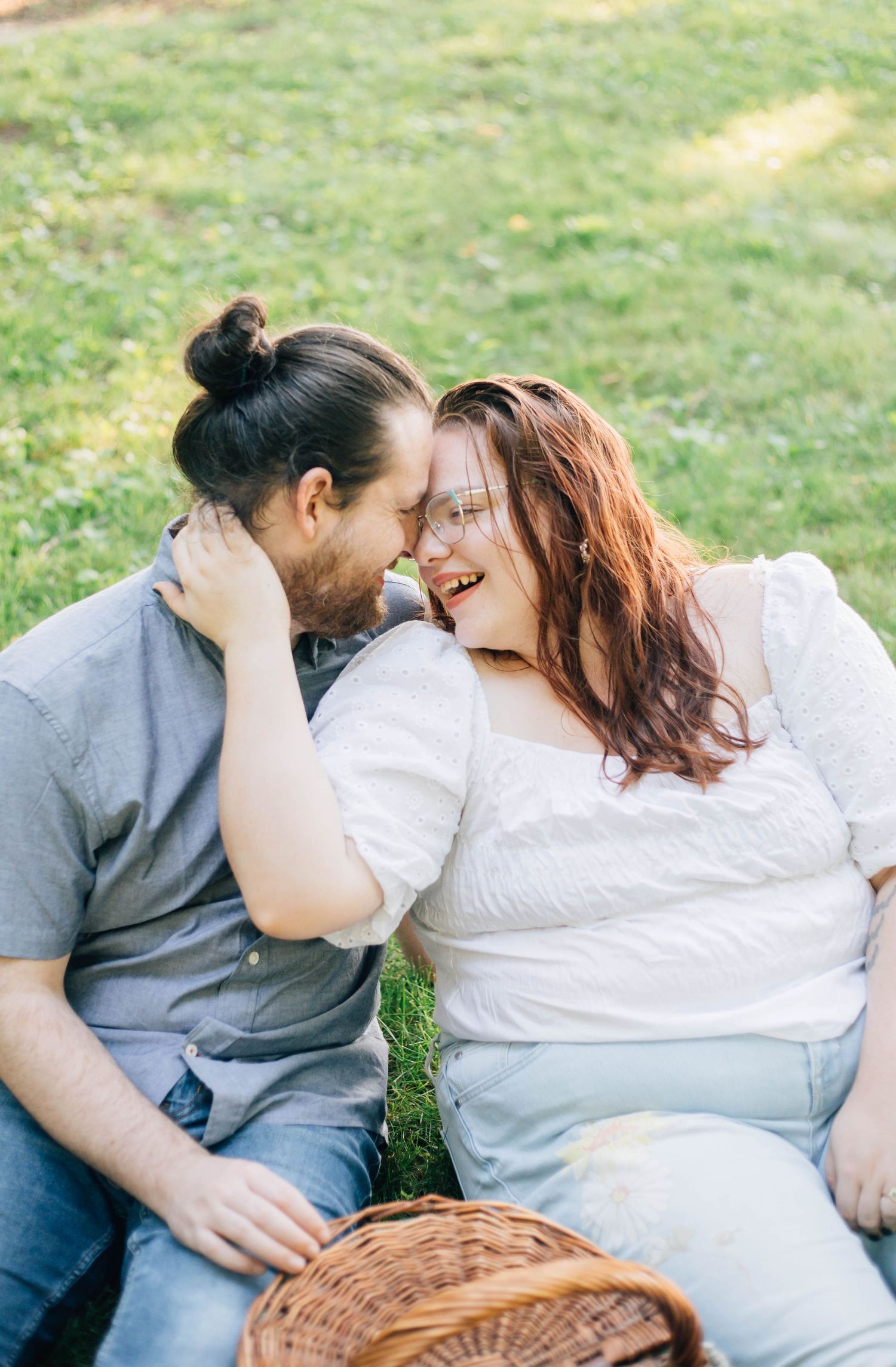 Happy couple sharing an intimate moment during a picnic on green grass with a wicker basket.