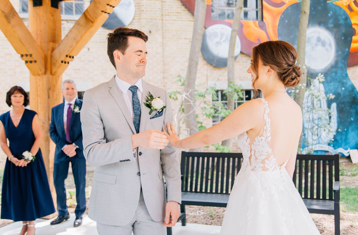 Wedding party guests applaud and celebrate under wooden pavilion during outdoor wedding ceremony.